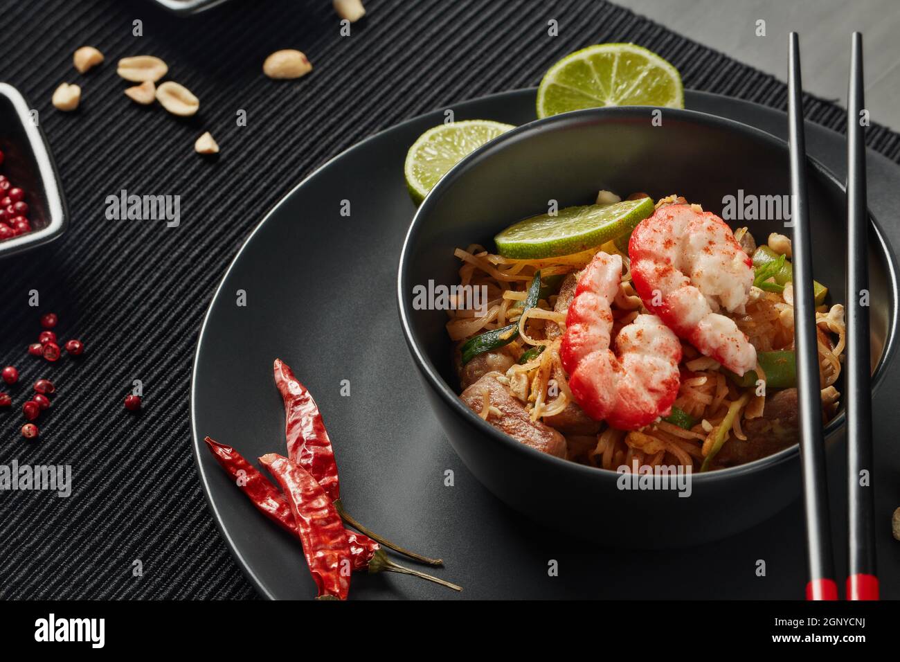 Pad Thai. Gebratene Reisnudeln mit Hühnerfleisch, Garnelen, Rührei, Erdnüssen, Gemüse und Sauce in einer Schüssel. Thailändisches Essen. Einstellungstabelle. Stockfoto