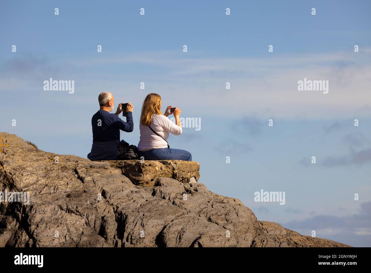 Touristen, die die Aussicht mit ihrem Telefon am Cwm-yr-Eglwys Beach, Dinas, Pembrokeshire, Wales fotografieren. VEREINIGTES KÖNIGREICH Stockfoto
