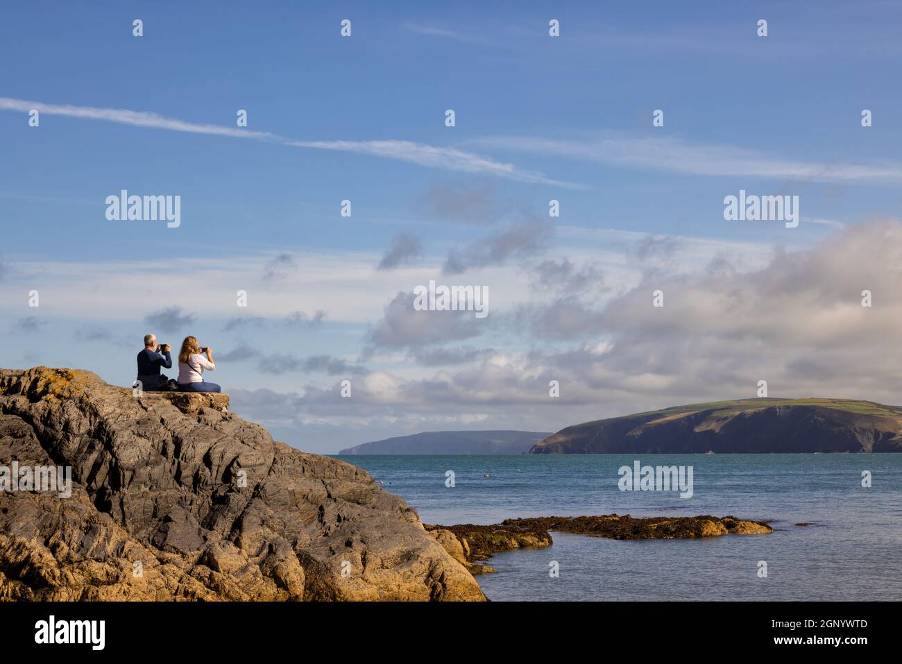 Touristen, die die Aussicht mit ihrem Telefon am Cwm-yr-Eglwys Beach, Dinas, Pembrokeshire, Wales fotografieren. VEREINIGTES KÖNIGREICH Stockfoto