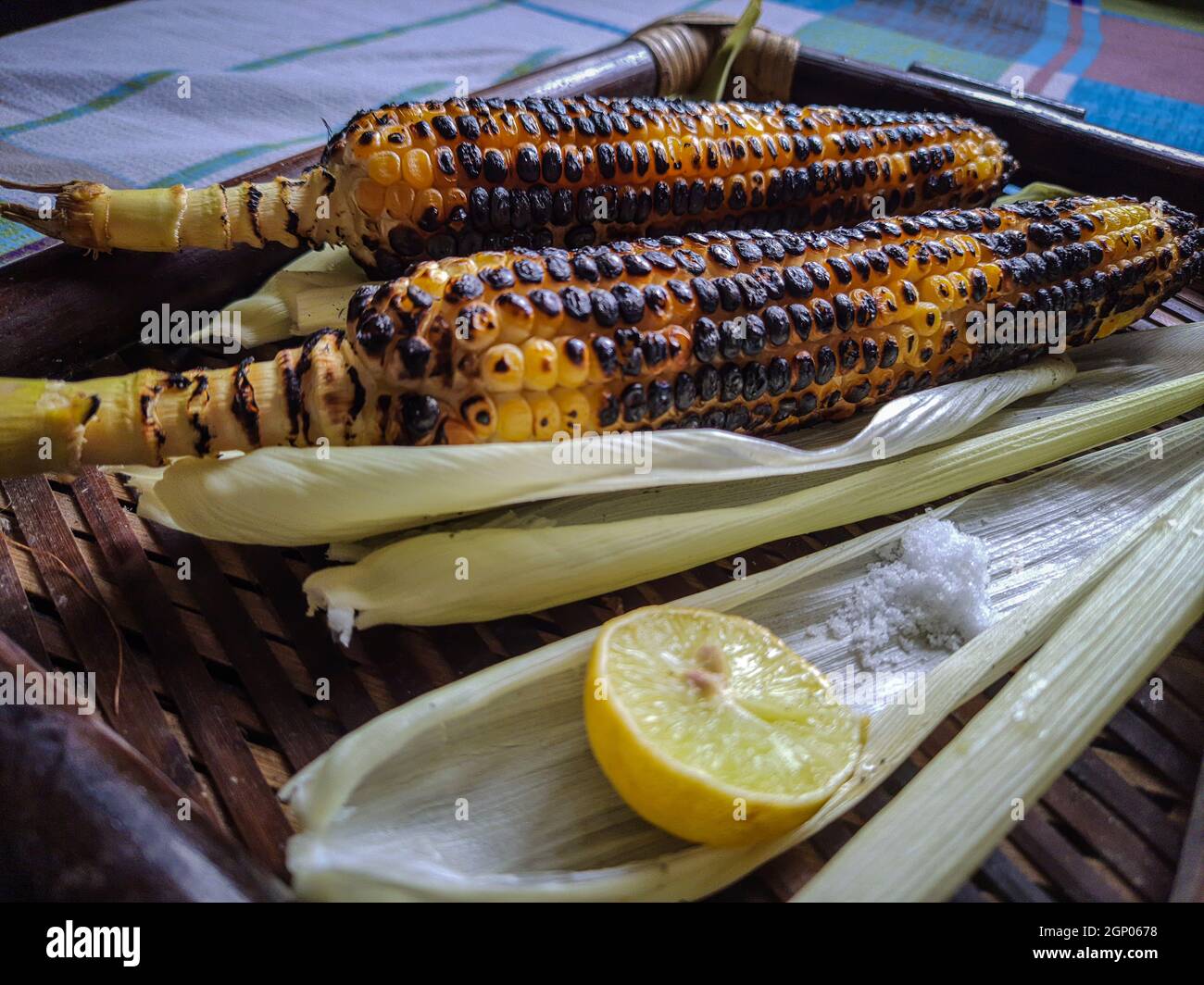 Würzig süßer Mais brennt mit Zitrone und Salz in einem Holztablett aus verschiedenen Blickwinkeln Stockfoto