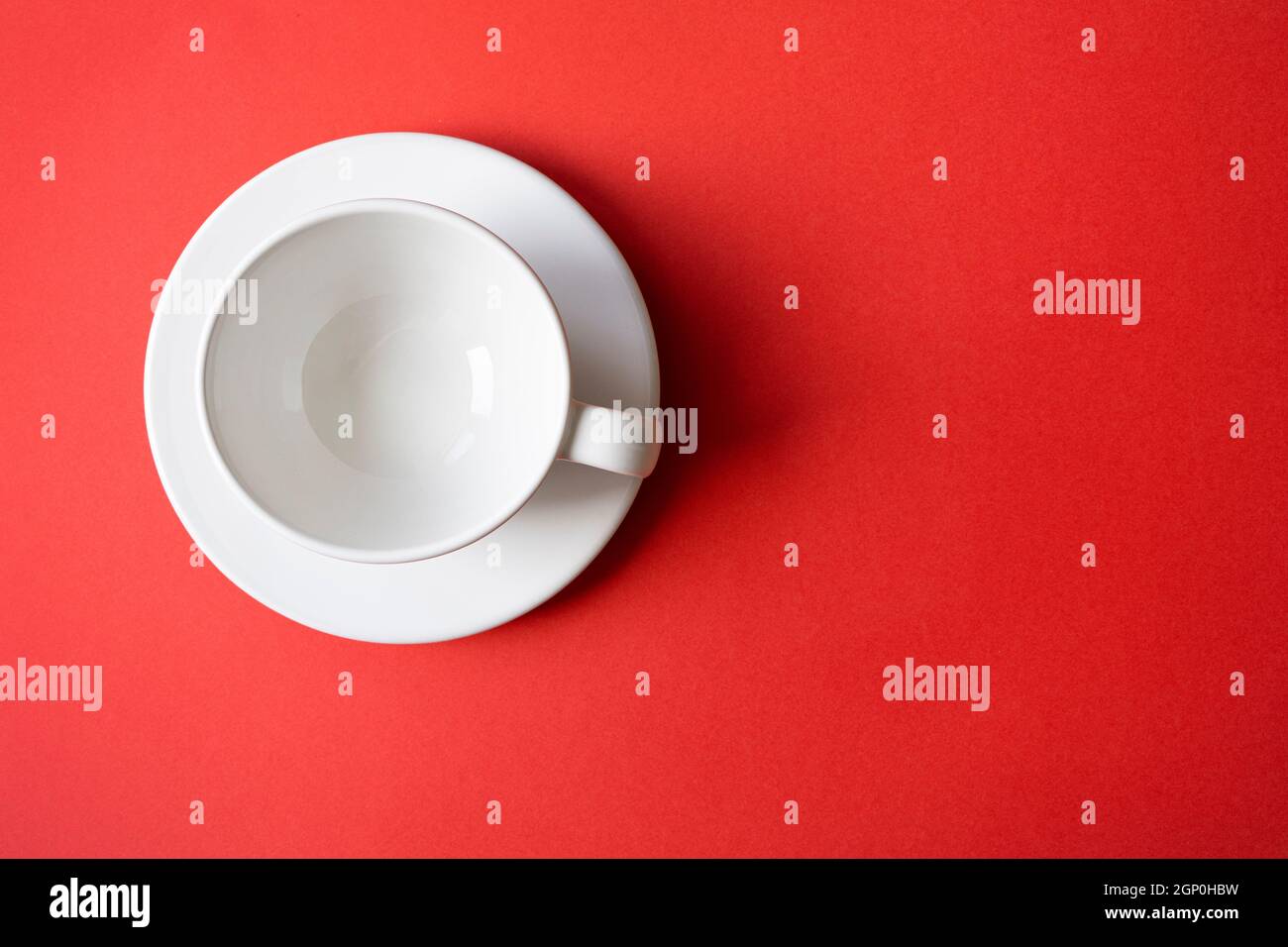 Einfache flache Lay-Komposition mit leerem weißen Keramikbecher, Becher, Schale auf einem Teller mit hellrotem Hintergrund, Draufsicht, Platz für Text Stockfoto