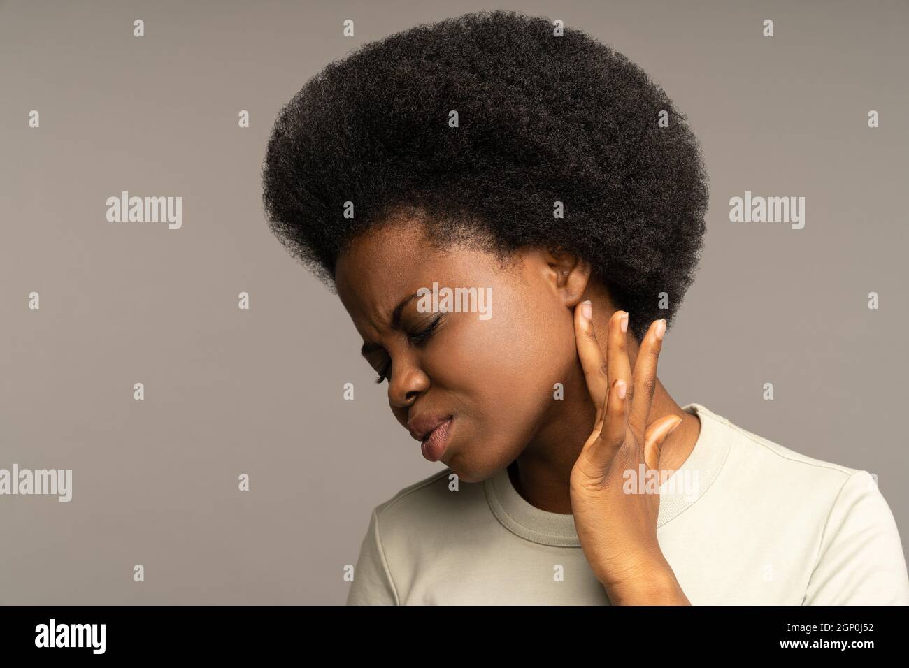 Krankes afrikanisches Mädchen, das Lymphknoten mit dem Finger überprüft, an Ohrenschmerzen, Otitis, Ohrerkrankungen leidet. Stockfoto