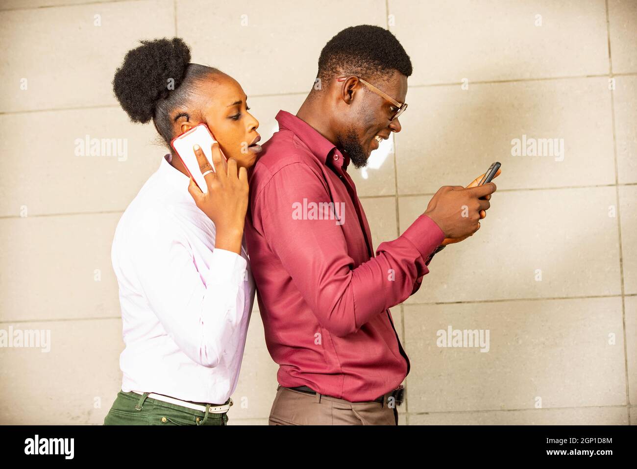 Ein junges, gutaussehend Paar steht zusammen und telefoniert mit Frau und Mann und schreibt eine Nachricht mit dem Mobiltelefon Stockfoto