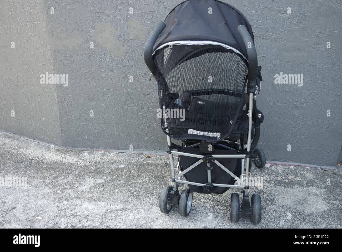 Schwarzer Baby Kinderwagen mit Kopfbedeckung. Kinderwagen ist mit Beton Hintergrund Stockfoto