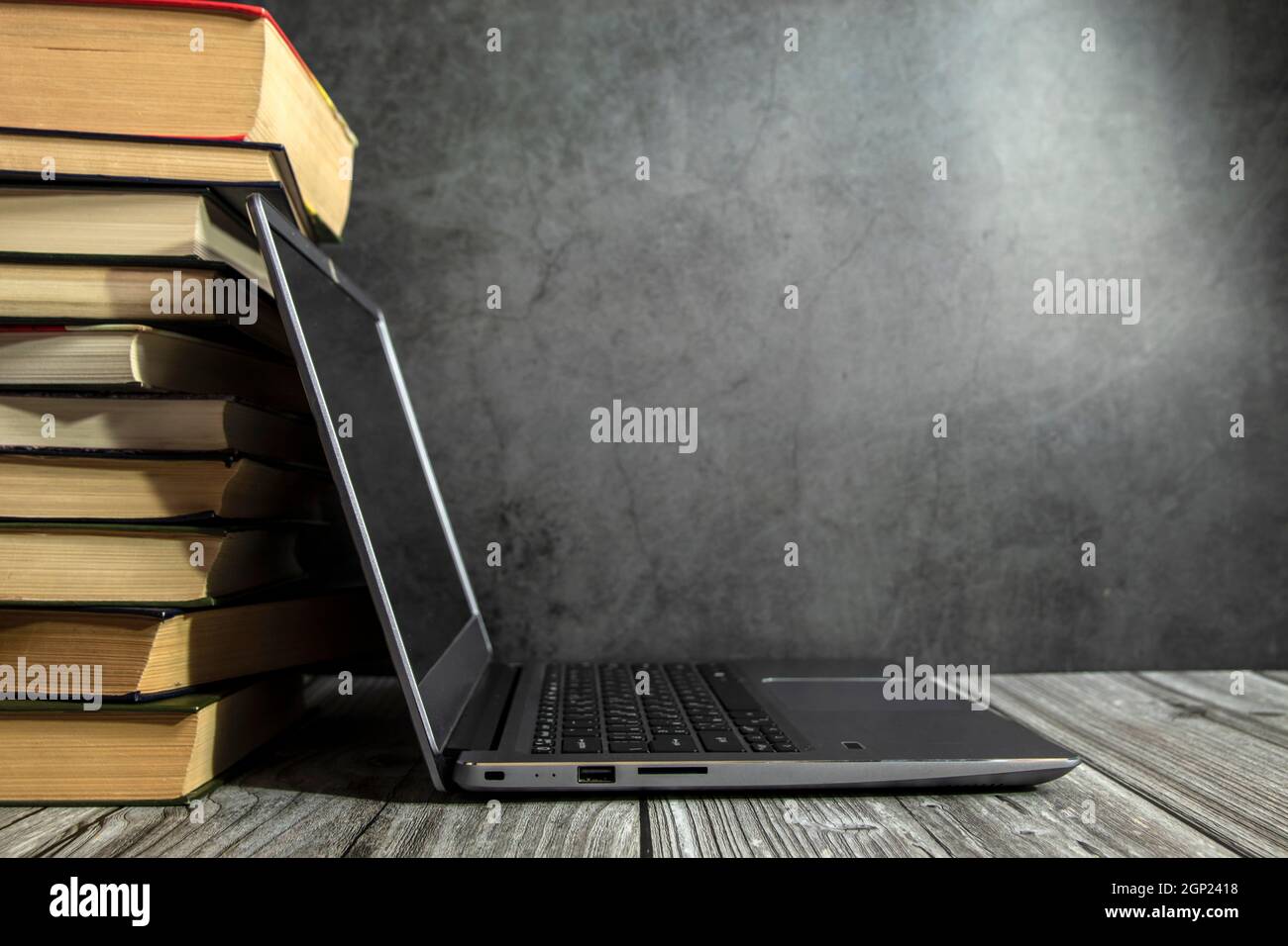 Ein offener Laptop auf dem Tisch in der Nähe des Bücherstapels. Stockfoto