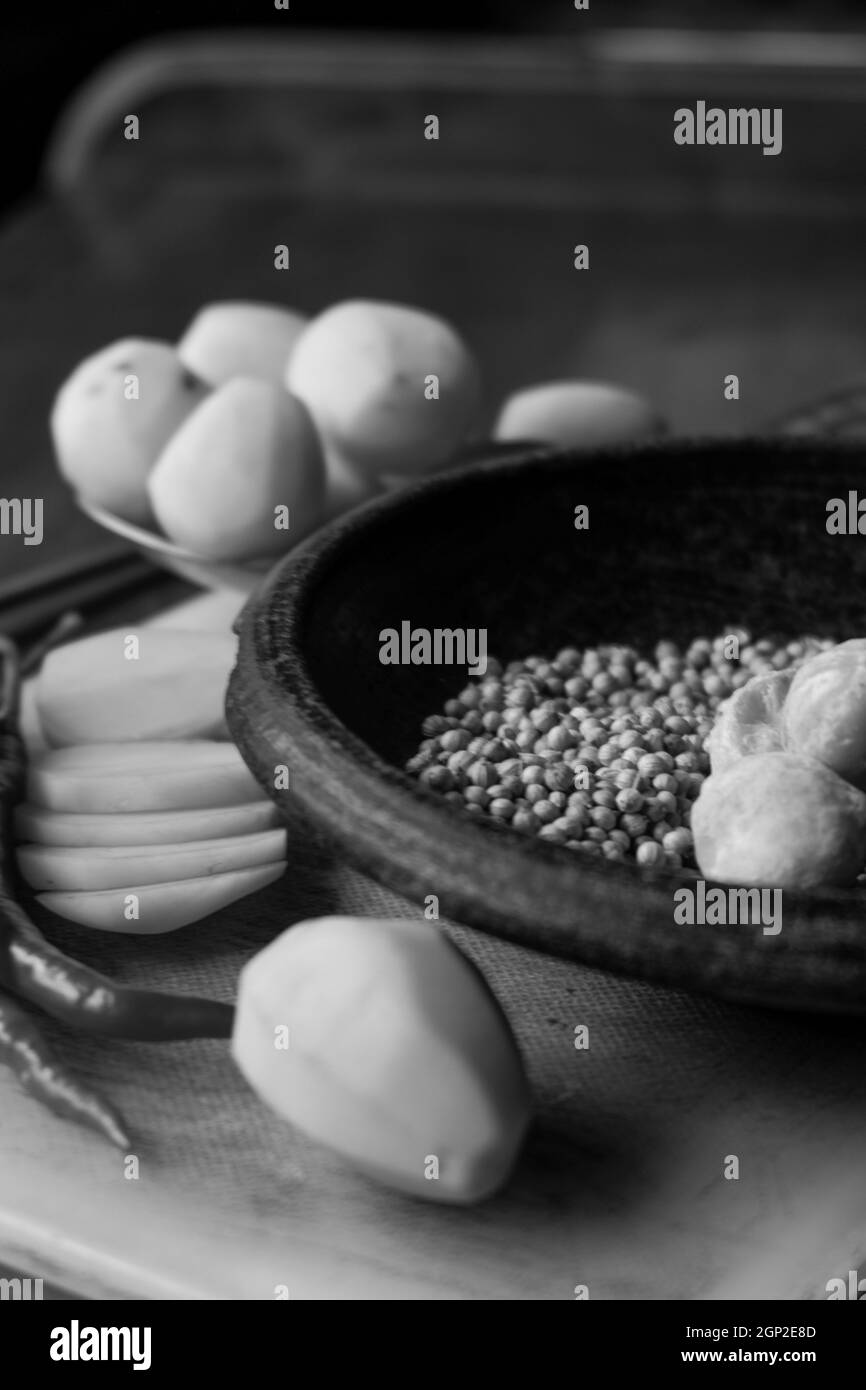 Nahauflistungen von Chilischoten, Pfeffer und Kartoffeln in einem Mörser mit einem Schwarz-Weiß-Motiv Stockfoto