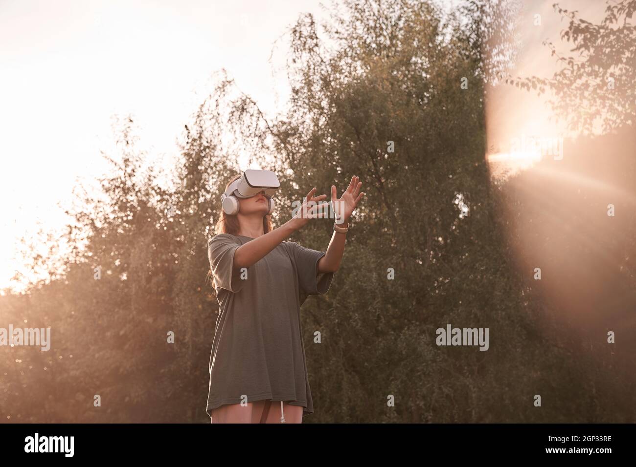 Ein Mädchen mit einer Virtual-Reality-Brille. Er reicht seine Hände an den Sonnenstrahl. Hochwertige Fotos Stockfoto