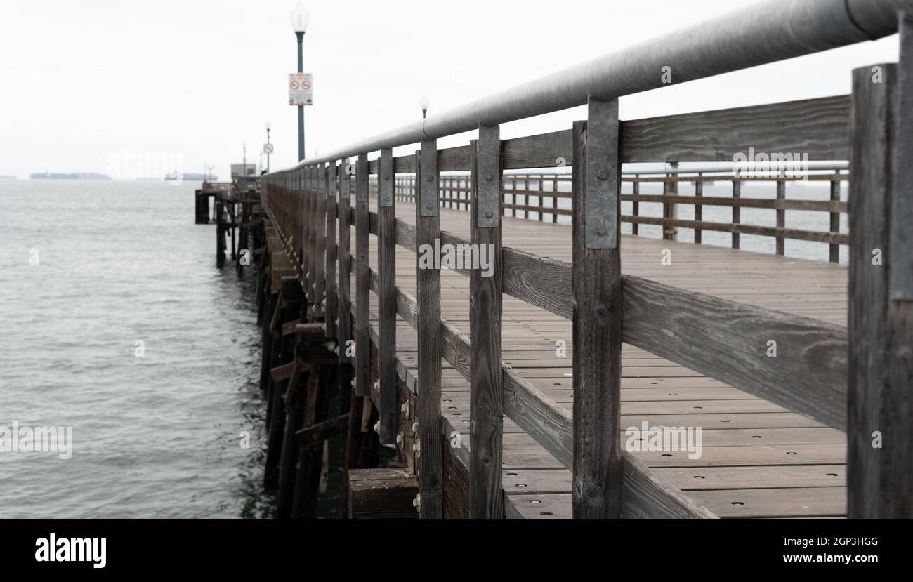 Containerschiffe warten auf den Zugang zum Hafen von Los Angeles, wie man vom Seal Beach Pier in Seal Beach, Kalifornien, USA, aus sieht Stockfoto