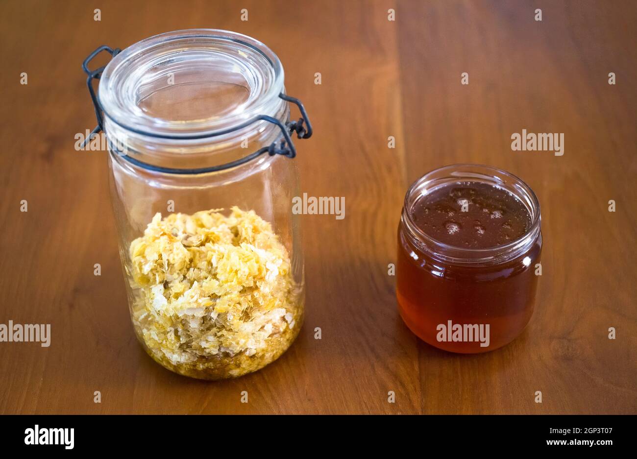 Bienenstock-Produkte: Honig und Bienenwachs in Glasgefäßen auf einem Holztisch Stockfoto