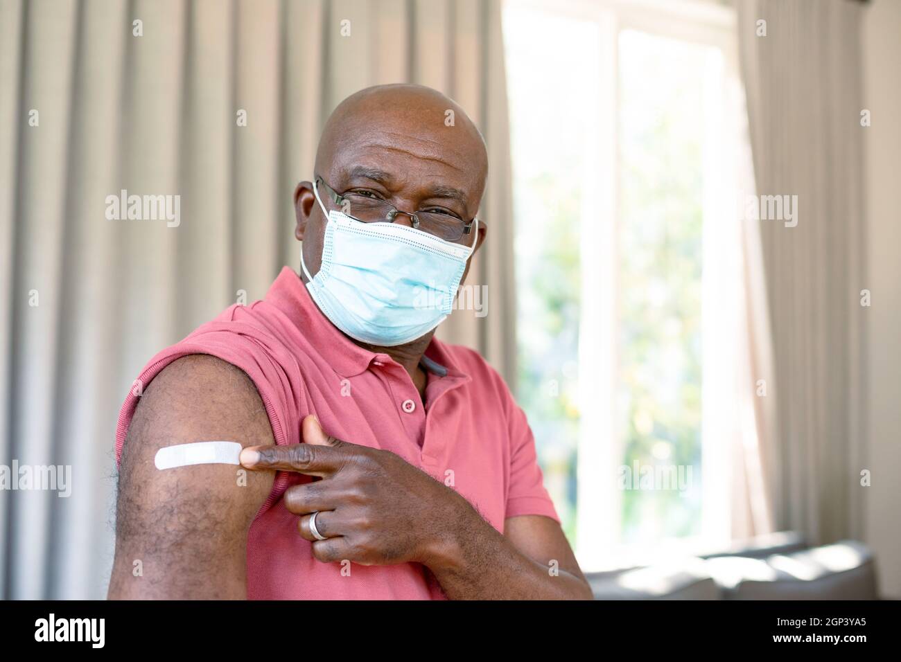 Älterer afroamerikanischer Mann mit Gesichtsmaske, der nach der Impfung Gips zeigt Stockfoto