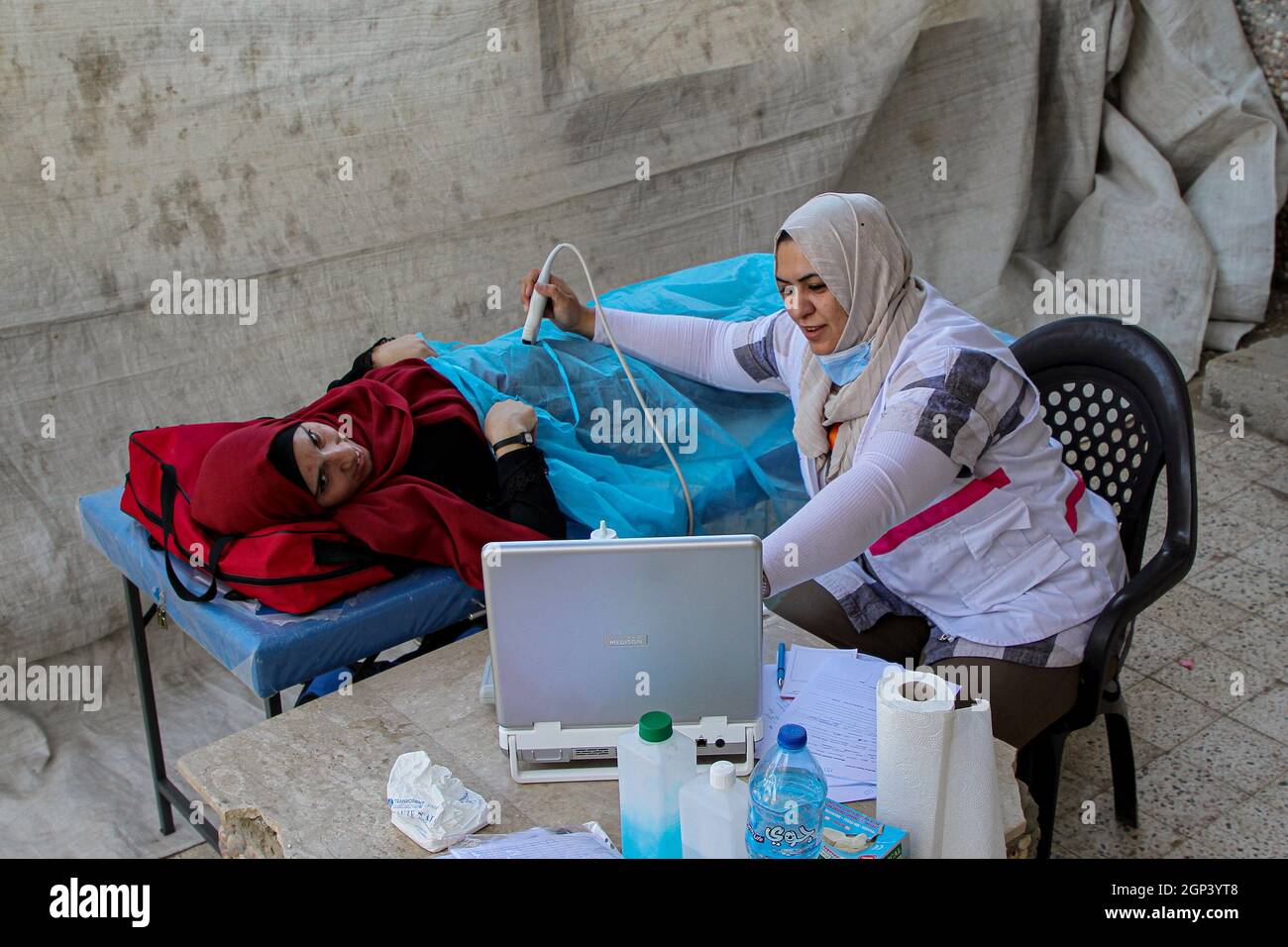 Gaza City, Gaza City. September 2021. Am 28. September 2021 bietet eine medizinische Mitarbeiterin einer Frau im Viertel al-Shejaiya, Gaza City, kostenlose medizinische Versorgung an. Viele Stunden am Tag ziehen mehrere mobile medizinische Kliniken von einem verarmten und abgelegenen Gebiet in ein anderes um, um den bedürftigen Bewohnern Gesundheitsdienste und Behandlungen zu bieten. DAZU „Feature: Mobile Kliniken bieten Gesundheitsdienste in verarmten, abgelegenen Gebieten von Gaza“. Quelle: Rizek Abdeljawad/Xinhua/Alamy Live News Stockfoto