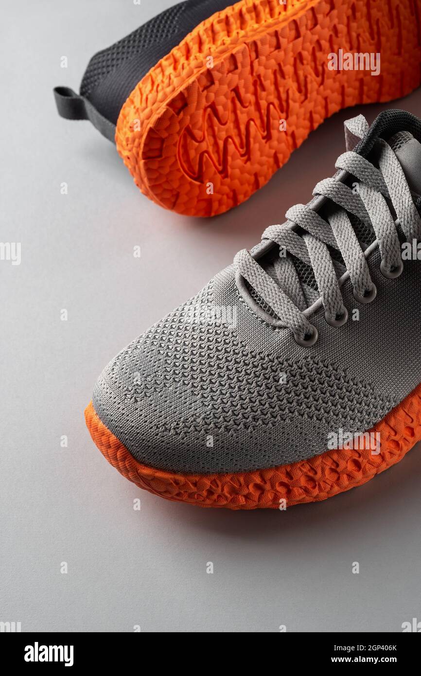 Gerillte, orange Sohle-Sneakers mit grauen elastischen Schnürsenkeln auf  grauem Hintergrund. Zwei neue Turnschuhe aus Mesh-Material für aktiven  Lifestyle und Fitness. Nahaufnahme Stockfotografie - Alamy