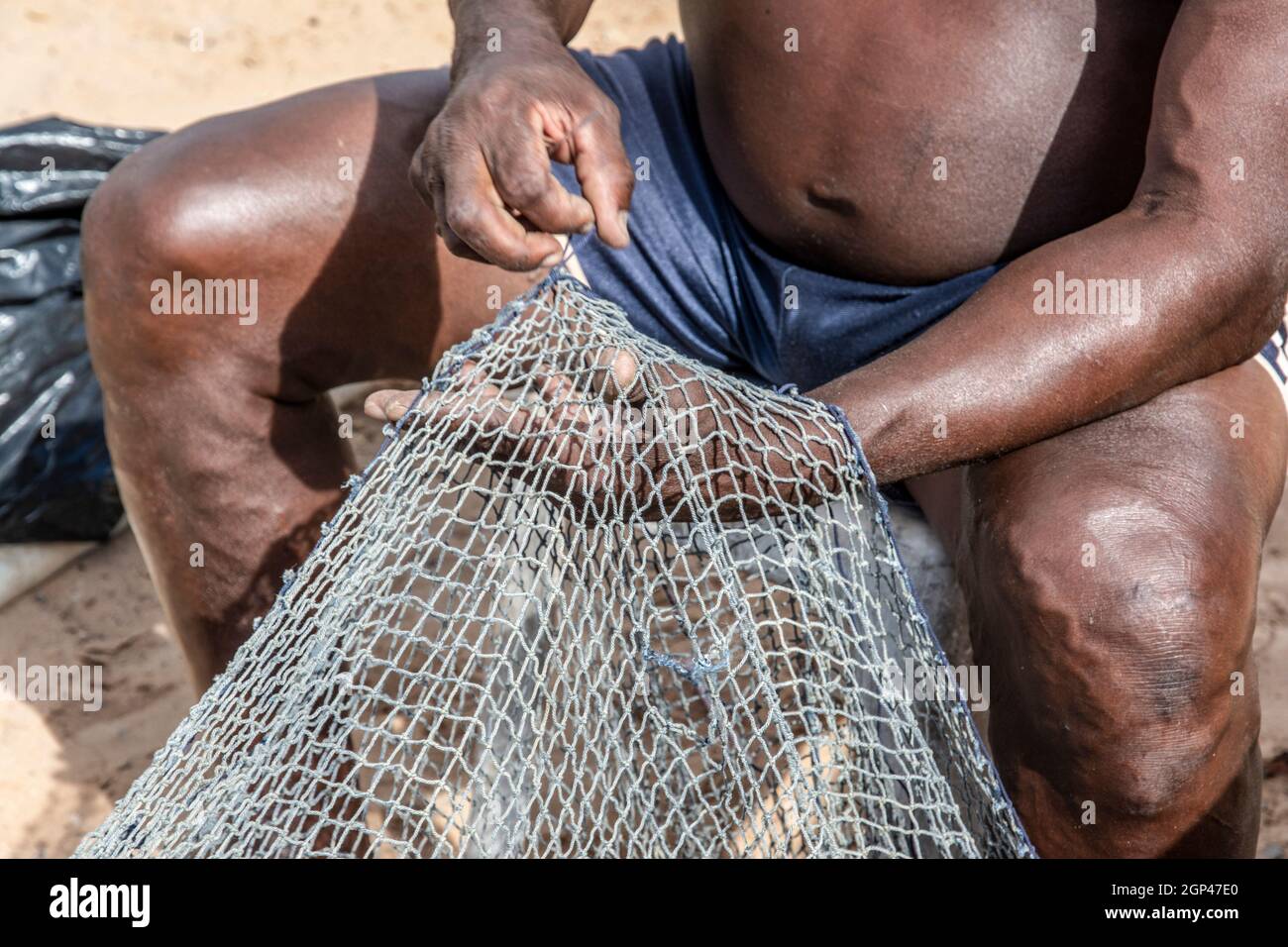 Salvador, Bahia, Brasilien - 08. Januar 2019: Fischer reparieren Fischernetz nach einer Zeit starker Nutzung. Stockfoto