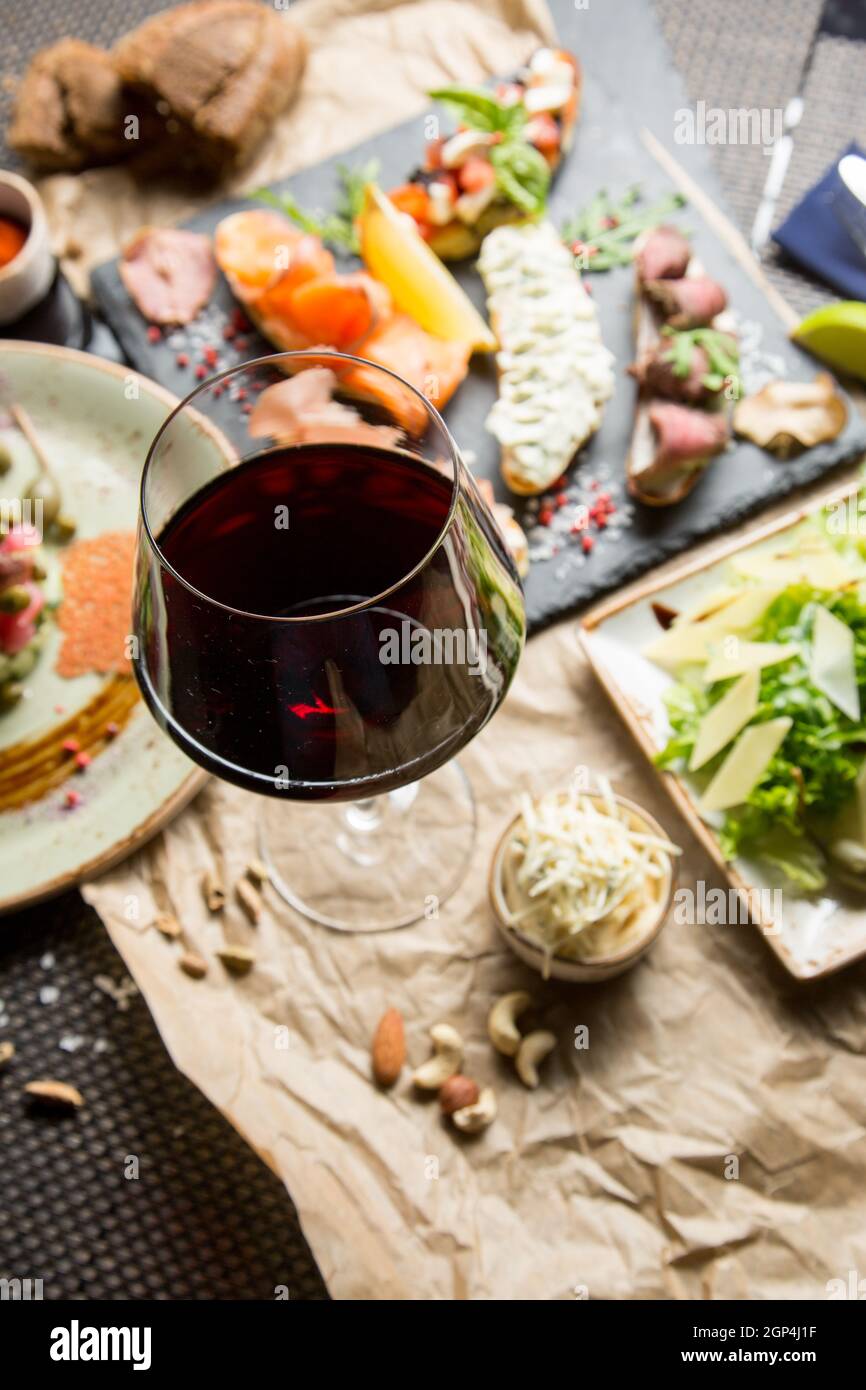 Ein Glas trockener Rotwein, ein Aperitif. Wein mit gegrilltem Fleisch und Gemüse. Konzept - Tischeinstellung in einem Restaurant. Stockfoto