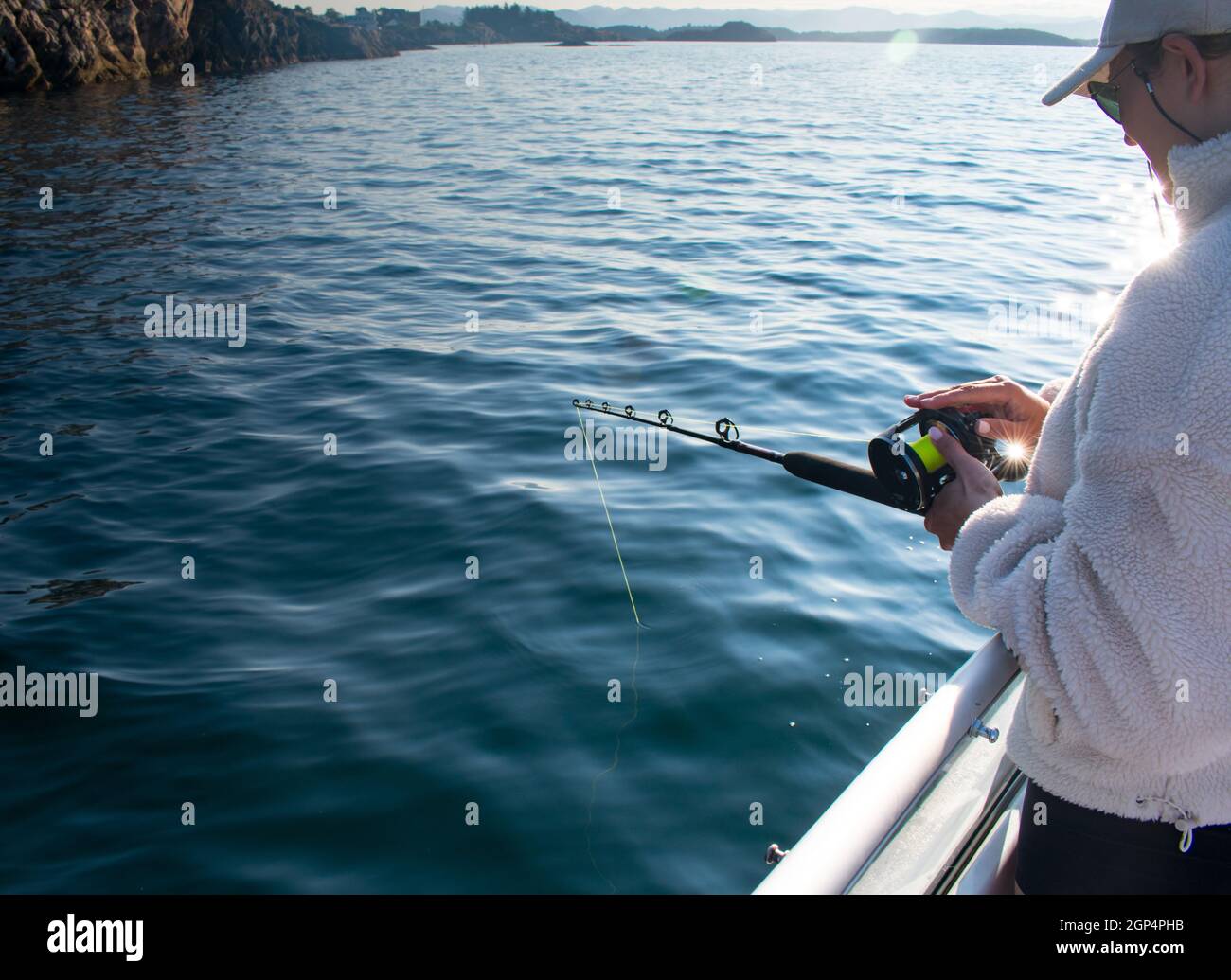 Fischerin mit Angelrute auf einem Boot im Meer bei Stavanger Norwegen (Jig Angeln) Stockfoto