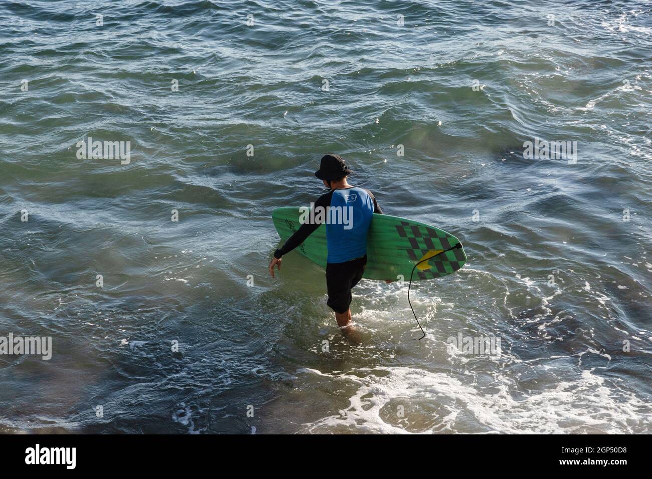 Salvador, Bahia, Brasilien - 17. Juni 2021: Surfer, die vom Strand Farol da Barra ins Meer kommen. Stockfoto