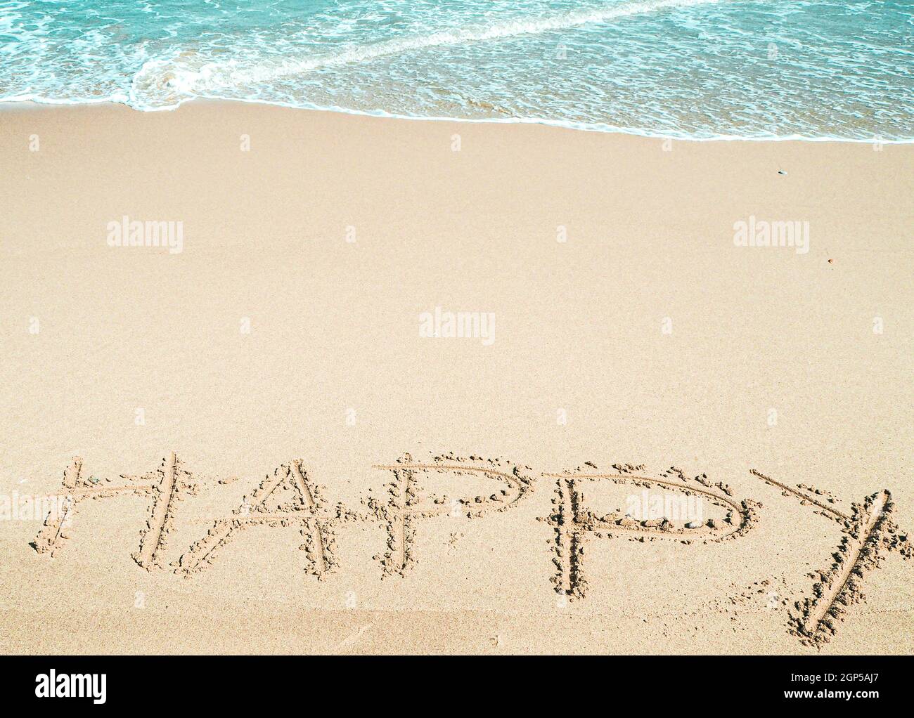 Frohe Worte am Strand. Glückliche handgeschriebene Worte auf Sand. Stockfoto