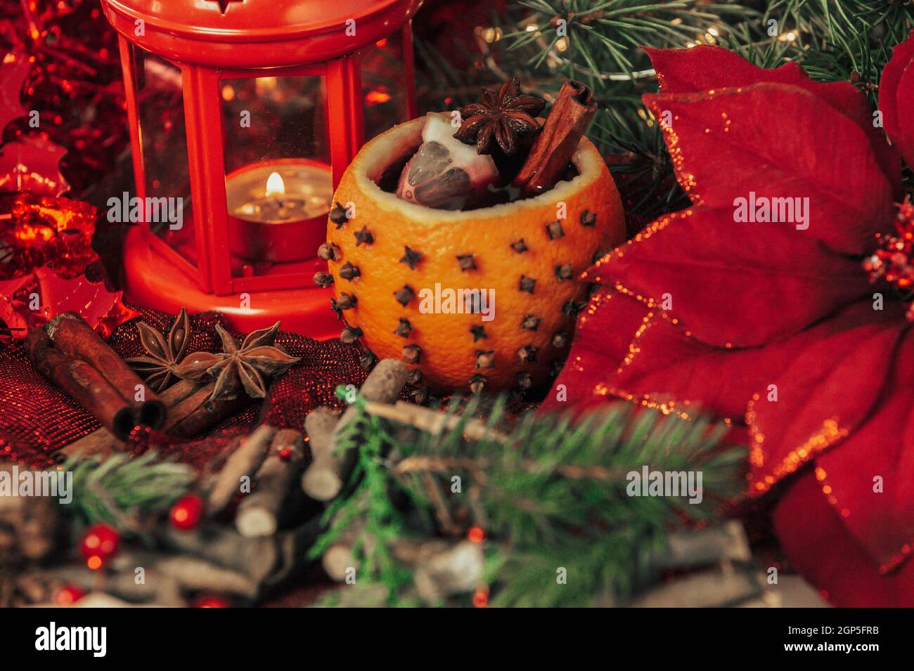 Weihnachtlich heißer Glühwein mit Gewürzen in Orange mit Dekorationen als Hintergrund Stockfoto