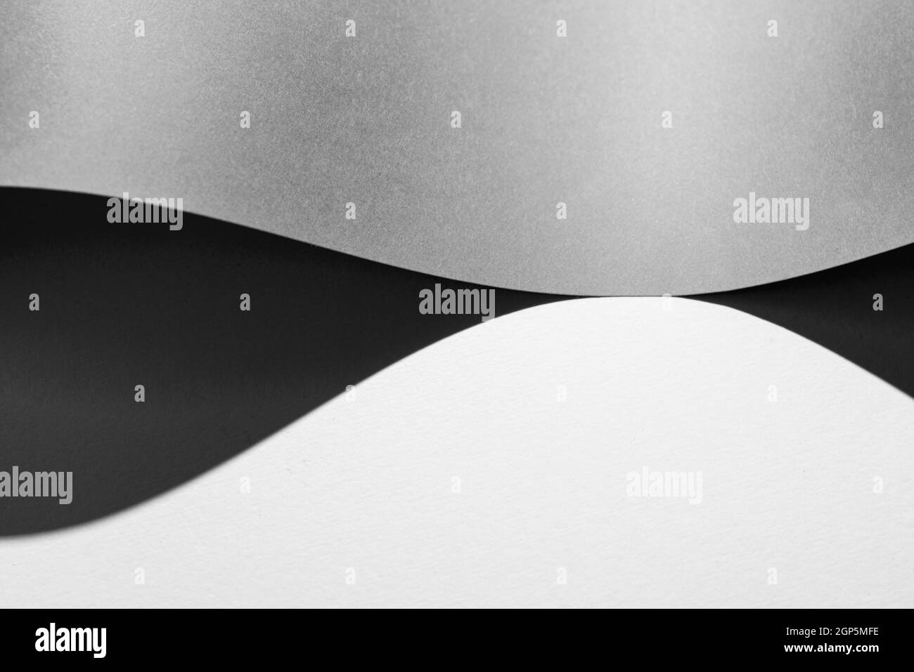 Der Schatten, der von einem Blatt Papier gebildet wird, das auf gefaltet ist Die weiße Oberfläche Stockfoto