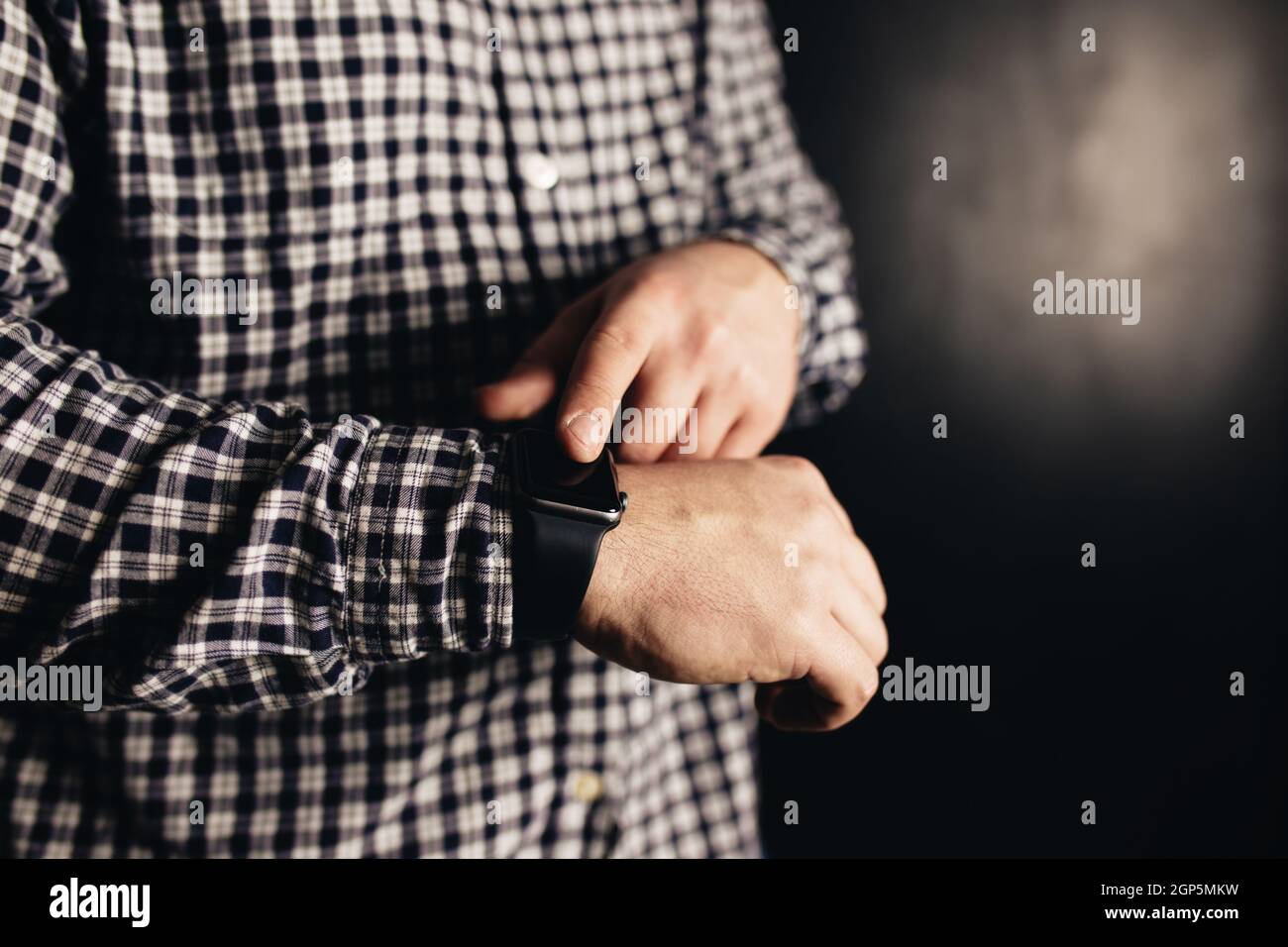 Mann in legerer Kleidung klickt Hand Uhren, Armband, schwarz verschwommen Hintergrund. Hochwertige Fotos Stockfoto