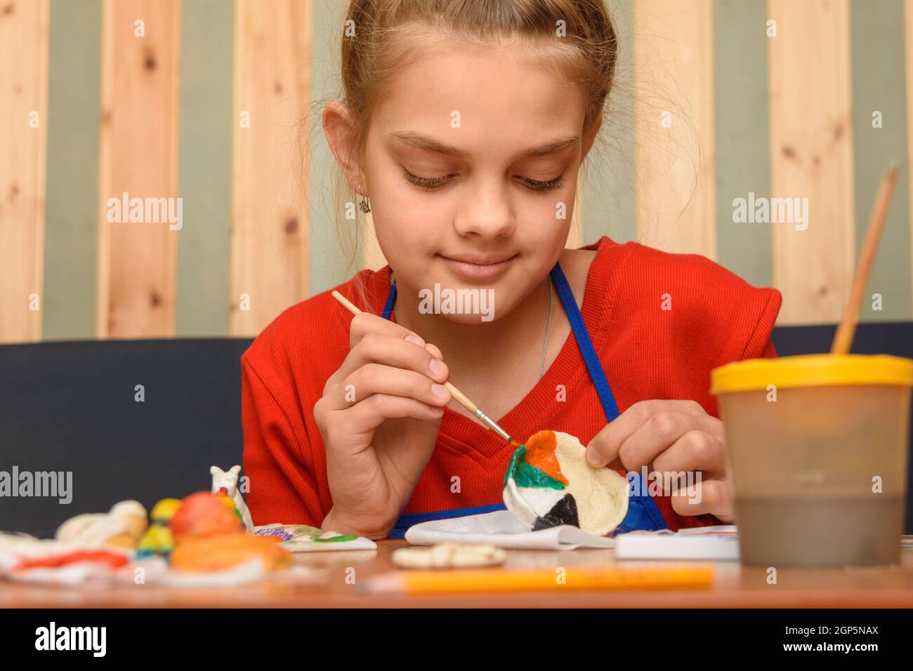 Ein Mädchen malt ein Handwerk aus Salzteig mit Aquarellen Stockfoto