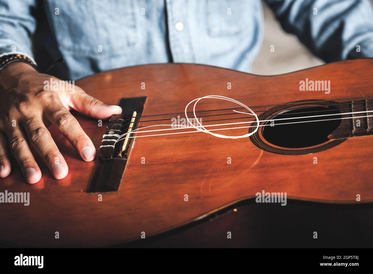 Nahaufnahme des Mannes, der zerbrechte Gitarrensaiten zeigt. Stockfoto