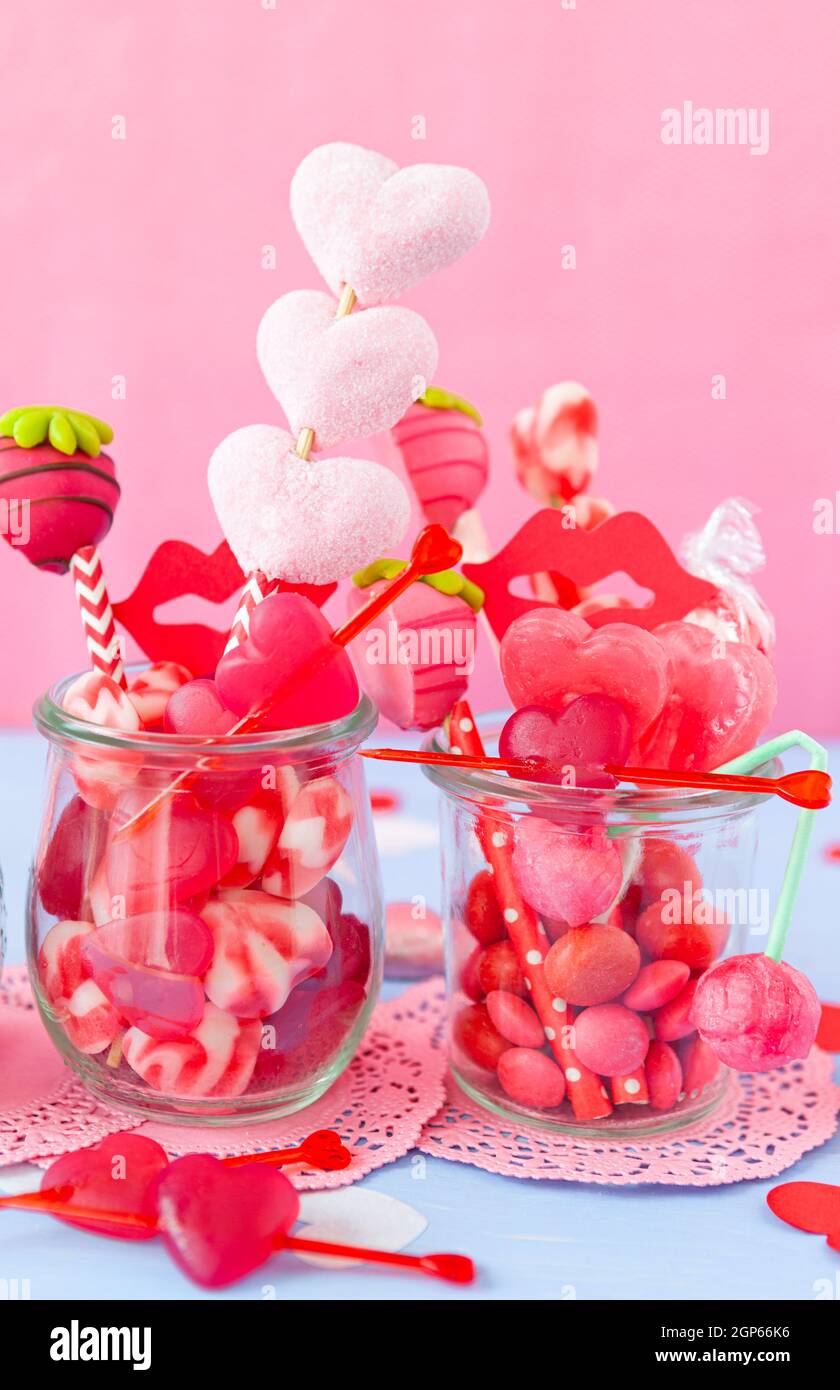 Kleines Glas mit niedlichen herzförmigen Süßigkeiten für Valentinstag Stockfoto