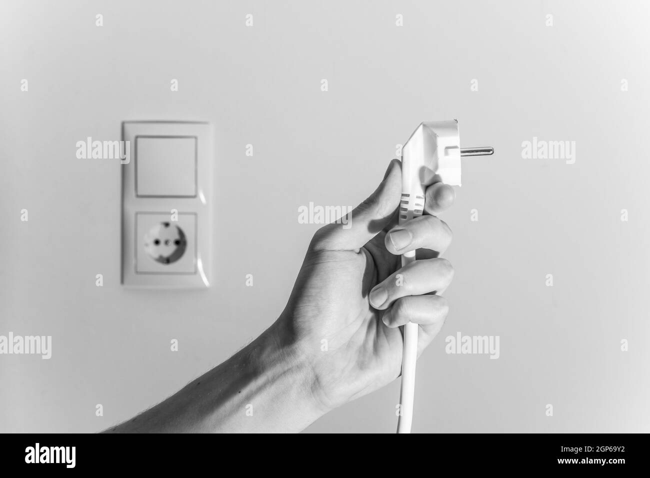 Den weißen Stecker mit Kabel in Männer hand, bereit, zu verbinden. Energiekonzept. Stockfoto