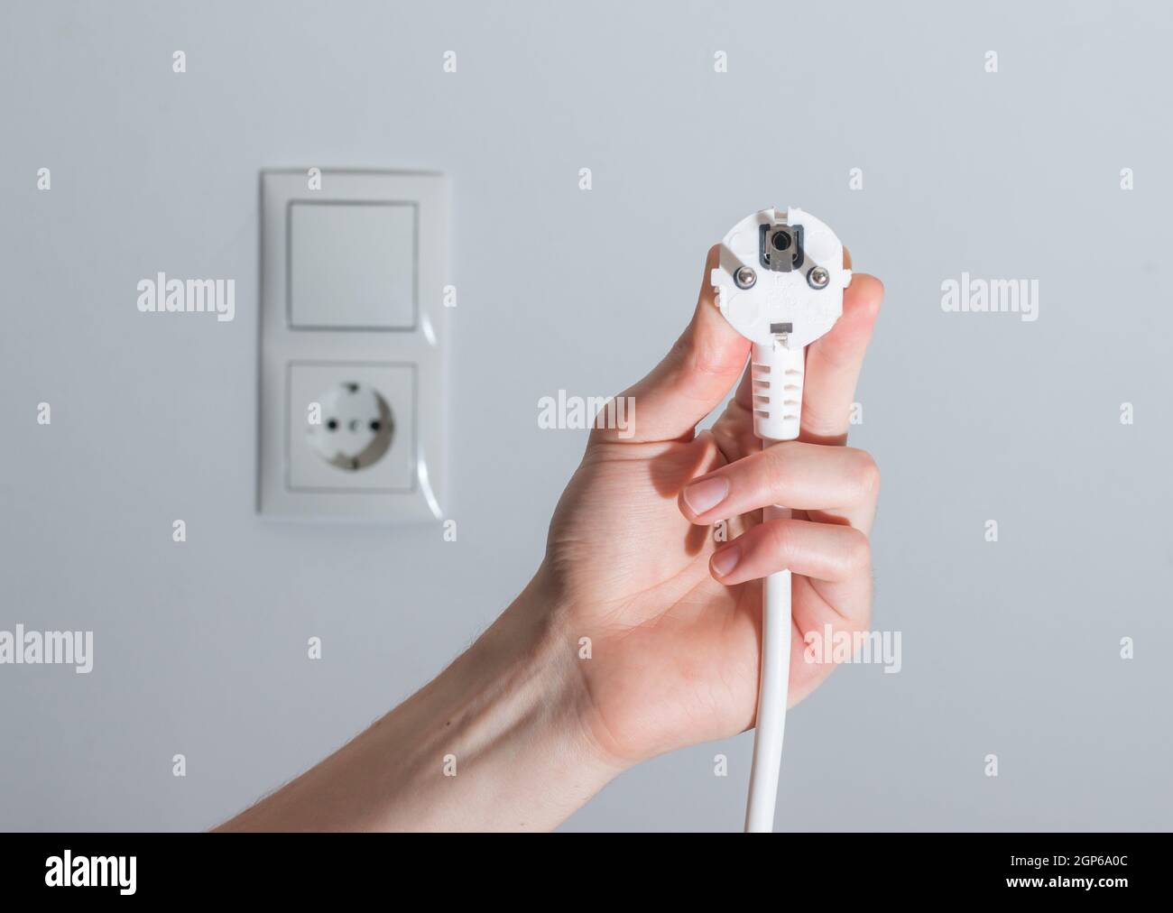 Den weißen Stecker mit Kabel in Männer hand, bereit, zu verbinden. Energiekonzept. Stockfoto