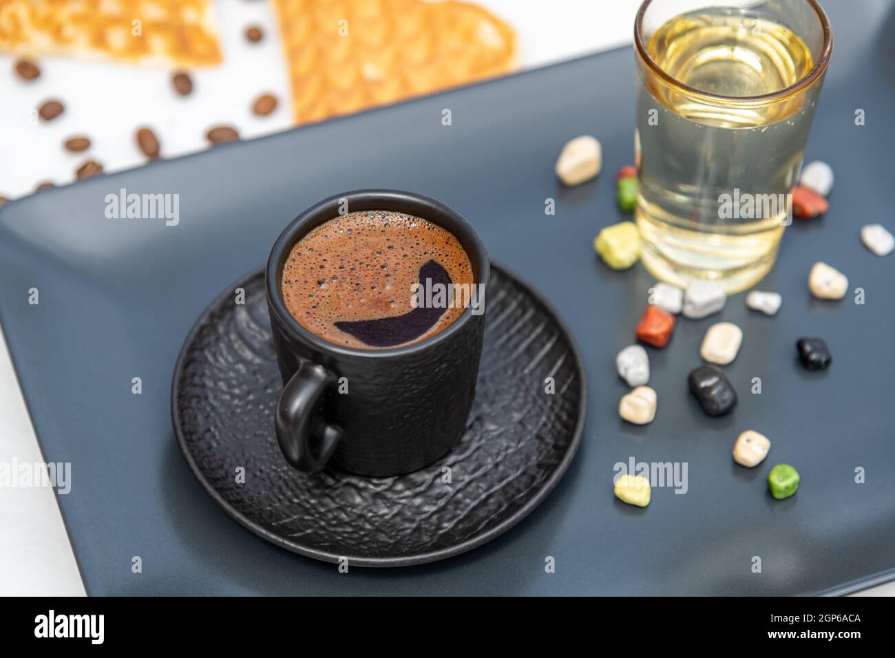 Traditioneller türkischer Kaffee in einer modernen schwarzen Tasse mit Wasser und Zucker. Selektiver Fokus Stockfoto