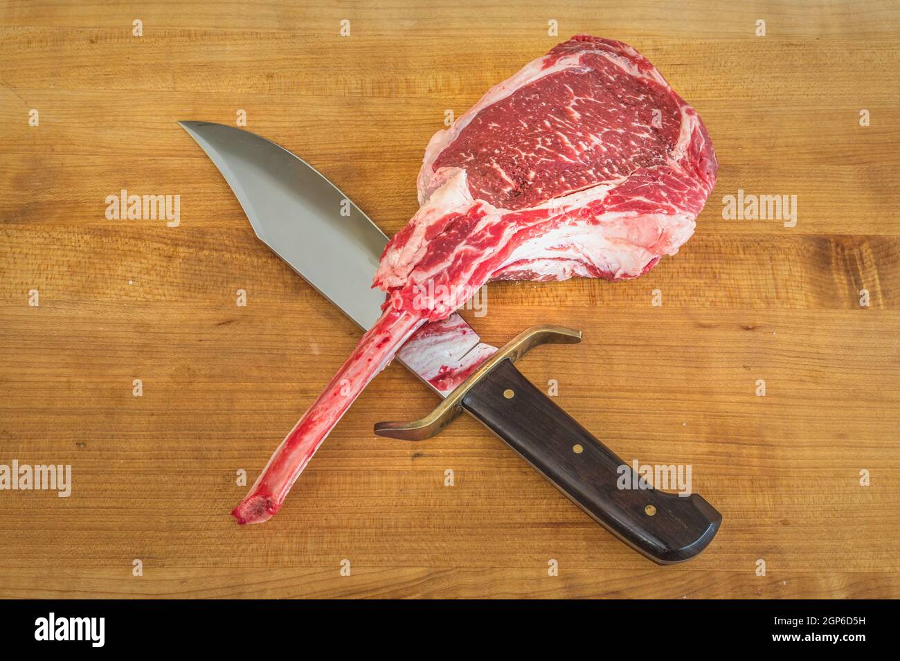 Rohes angus Tomahawk Steak auf einem Holzbrett mit einem Messer Stockfoto