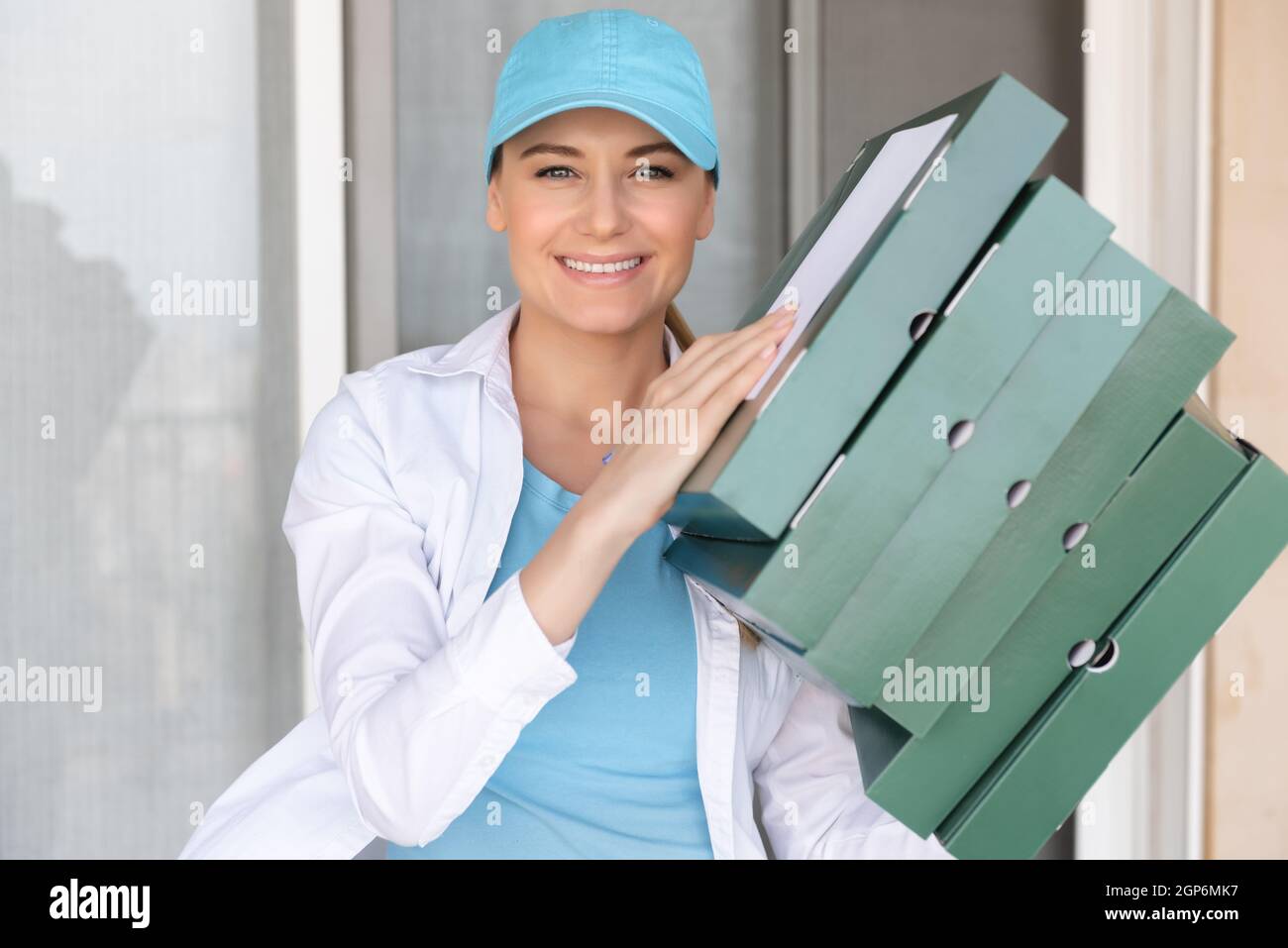 Portrait eines glücklichen lächelnden Liefermädchens mit Pizzaschachteln. Genießen Sie ihre Beschäftigung. Leckere Heiße Pizza. Fast Food. Online-Bestellung. Sommerjob. Stockfoto