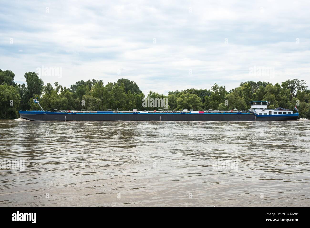Tankerschiff segelt am bewölkten Sommertag einen Fluss hinauf Stockfoto