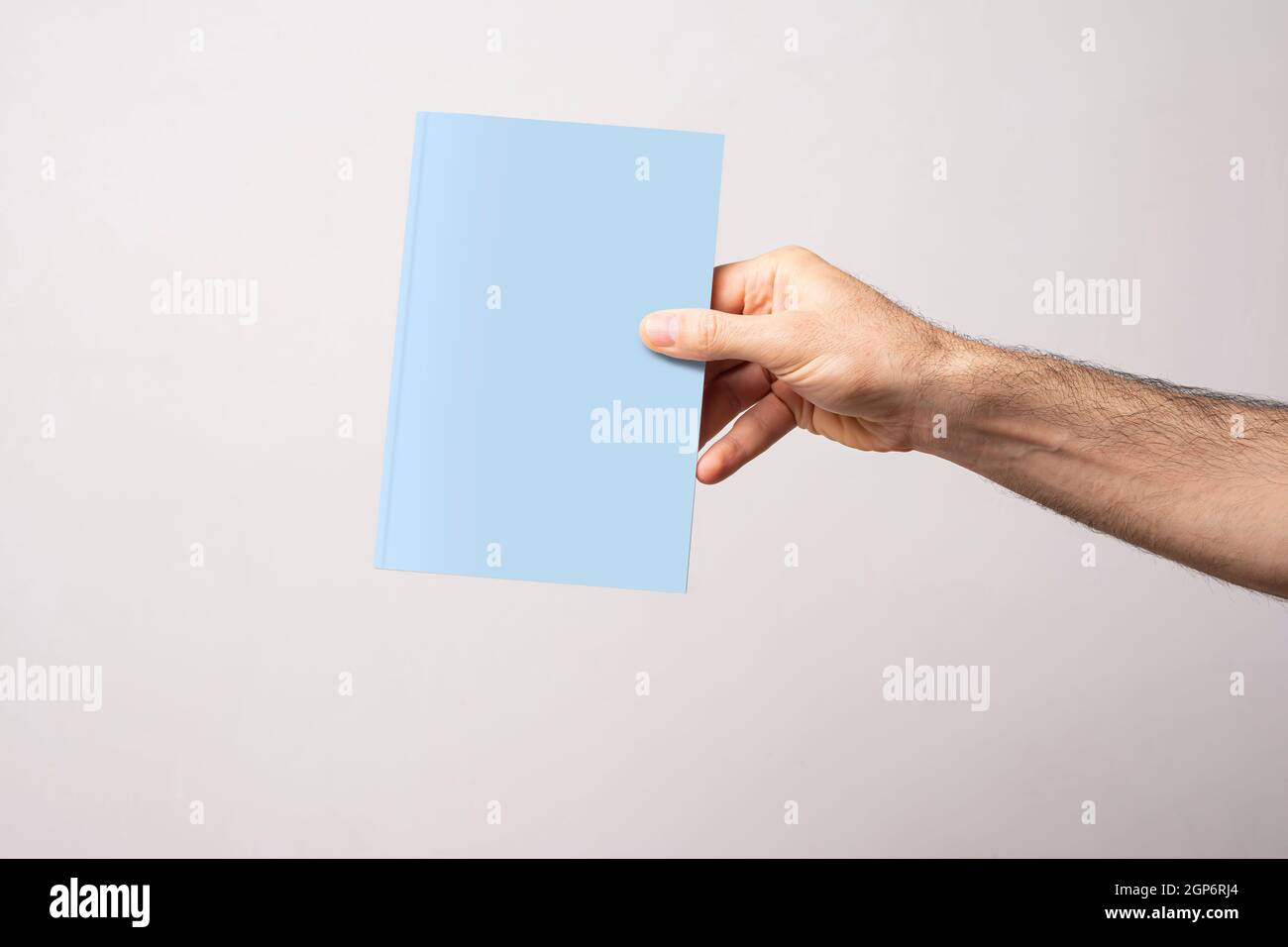 Männliche Hand mit geschlossenem Buch-Katalog mit leerem Cover, Modell-Serienvorlage bereit für Ihr Design, Buchcover-Auswahlweg ausgeschlossen. Stockfoto