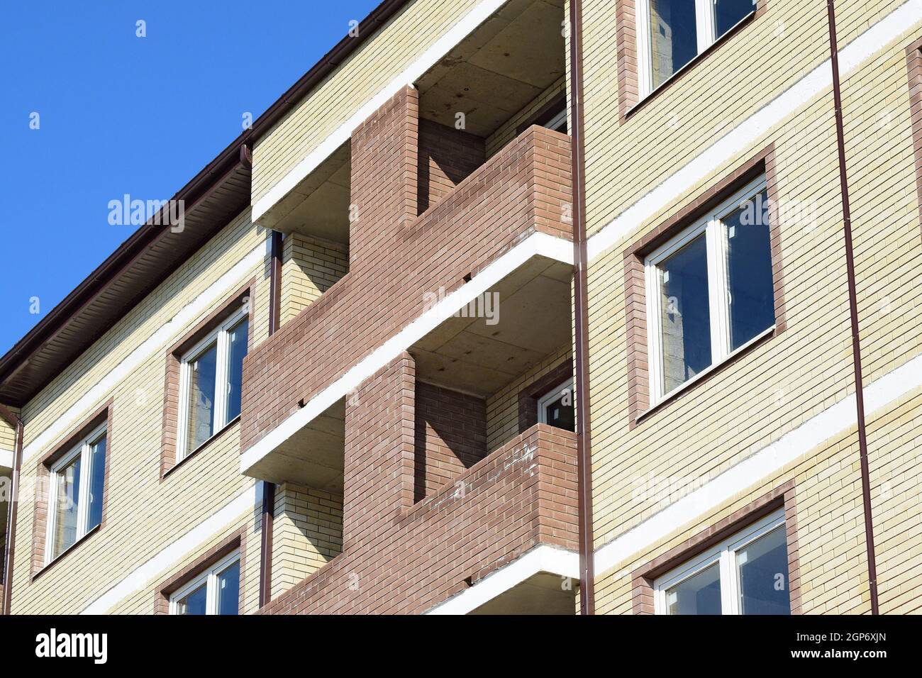 Balkone und Fenster ein mehrgeschossiges neues Haus. Neues Haus aus Backstein. Stockfoto