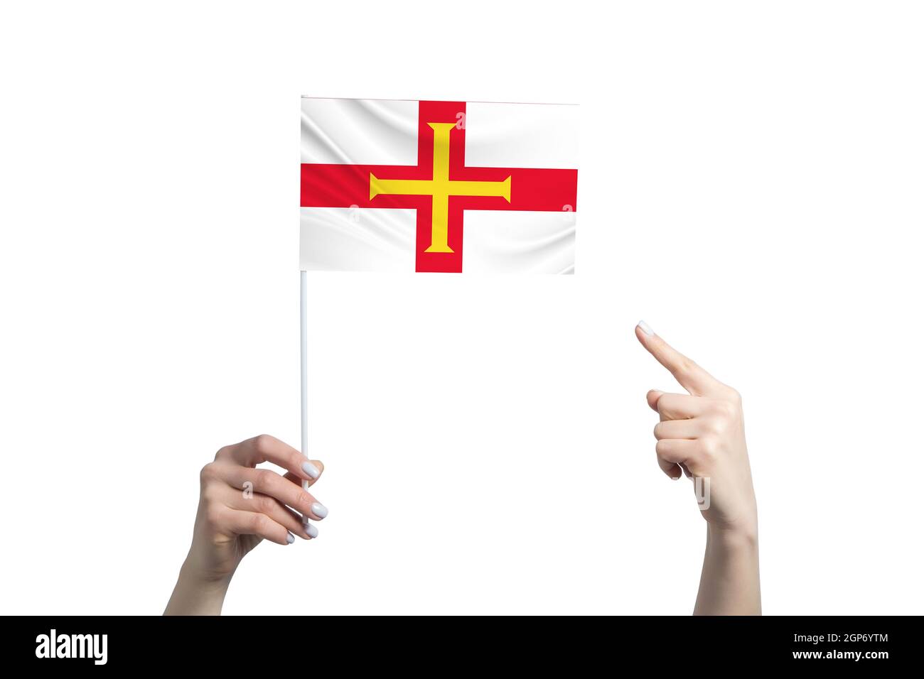 Eine schöne weibliche Hand hält eine Guernsey-Fahne, auf der sie den Finger ihrer anderen Hand zeigt, isoliert auf weißem Hintergrund Stockfoto