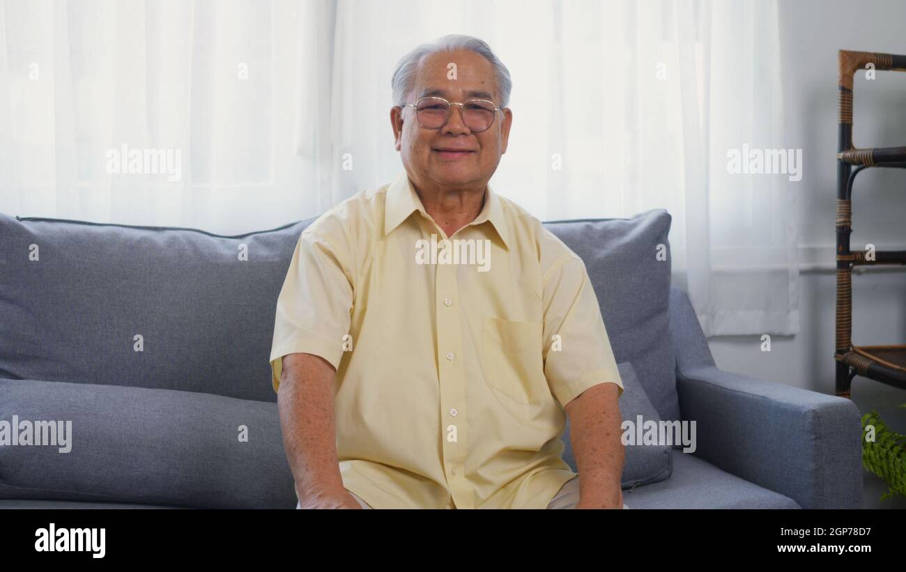 Kopf erschossen Porträt alter Mann Großvater Lächeln mit Brillen entspannend Blick auf die Kamera, asiatische glücklich Senior alten grauhaarigen sitzen im Wohnzimmer Stockfoto