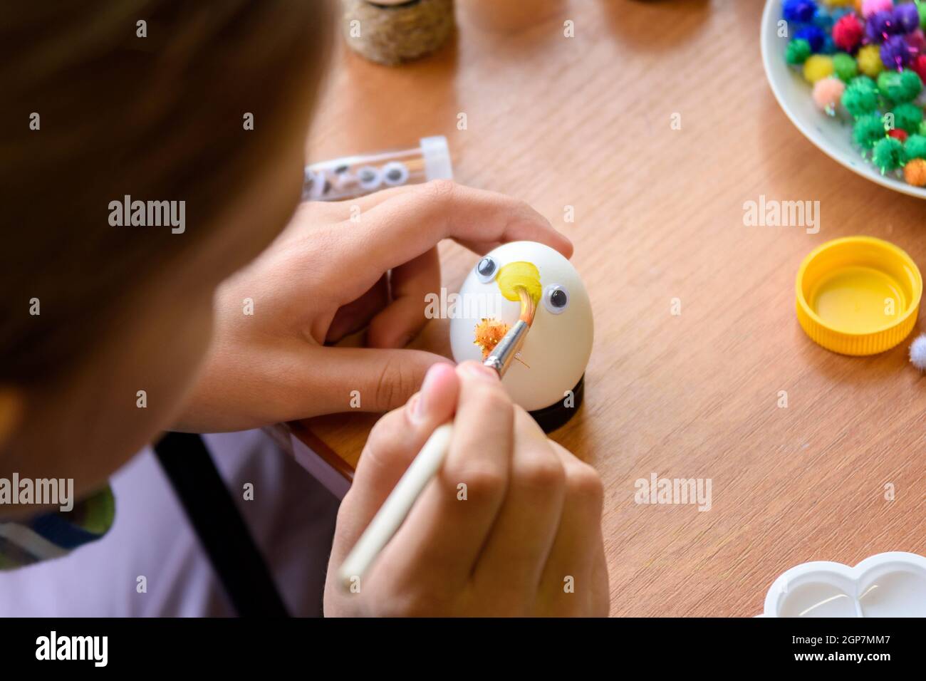 Nahaufnahme der Hände eines Kindes, das Ostereier malt Stockfoto