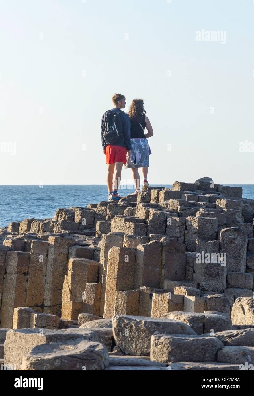 Junges Paar, das auf Basaltsäulen steht, The Giant's Causeway, Causeway Coast, in der Nähe von Bushmills, County Antrim, Nordirland, Vereinigtes Königreich Stockfoto