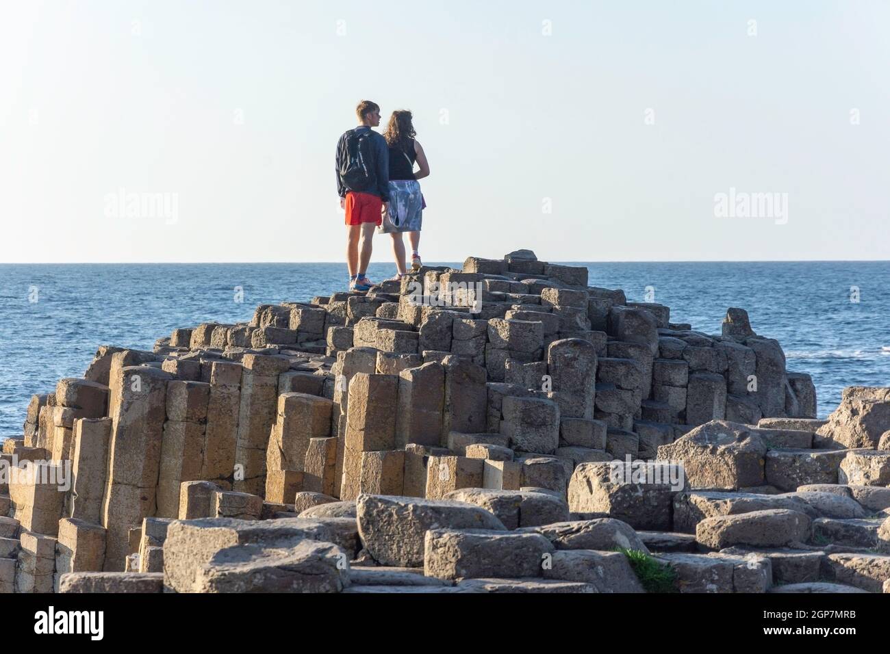 Junges Paar, das auf Basaltsäulen steht, The Giant's Causeway, Causeway Coast, in der Nähe von Bushmills, County Antrim, Nordirland, Vereinigtes Königreich Stockfoto