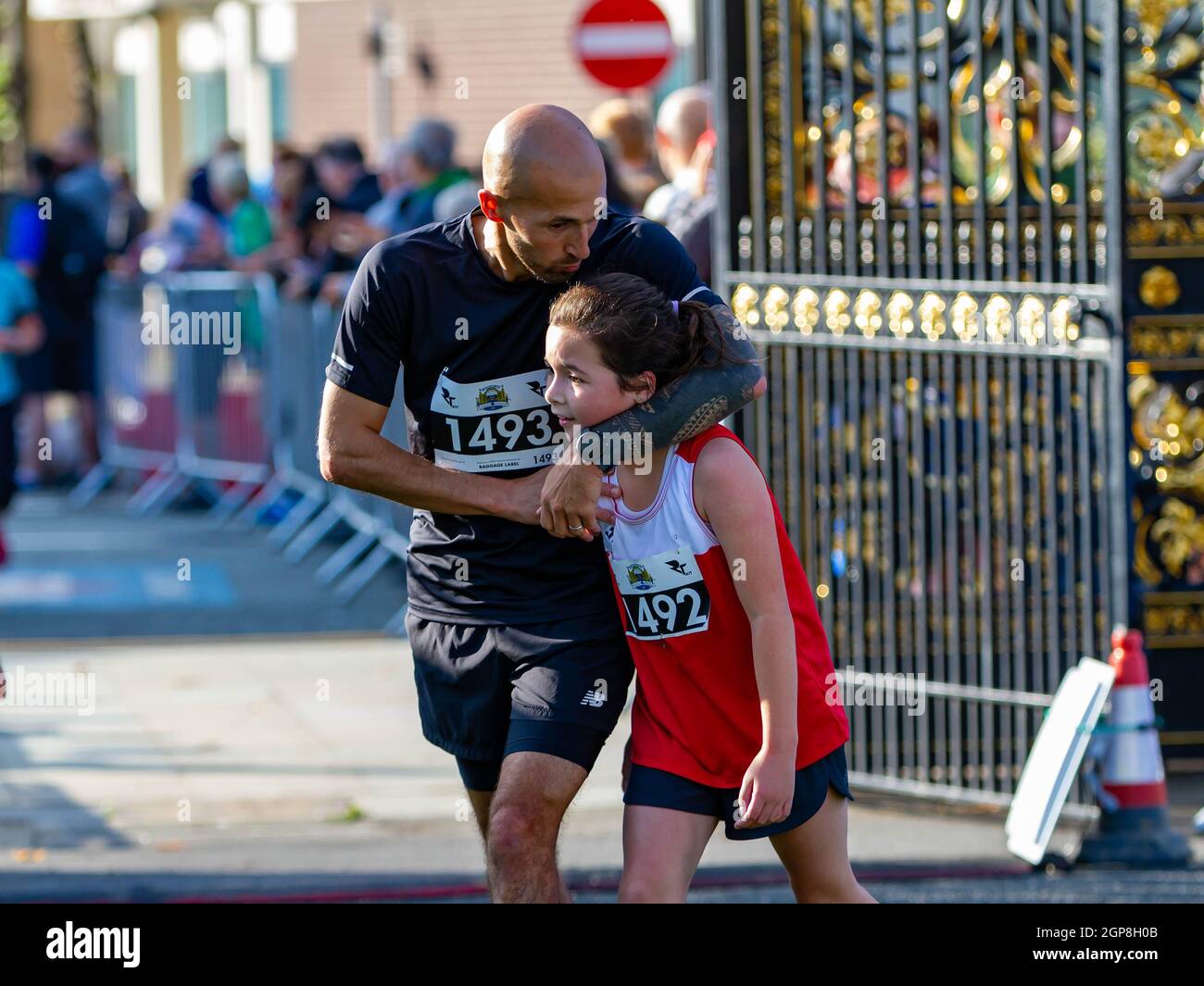 Warrington Running Festival 2021 - das junge Mädchen überquert die Ziellinie mit ihrem Vater, der sie umarmt und küsst Stockfoto
