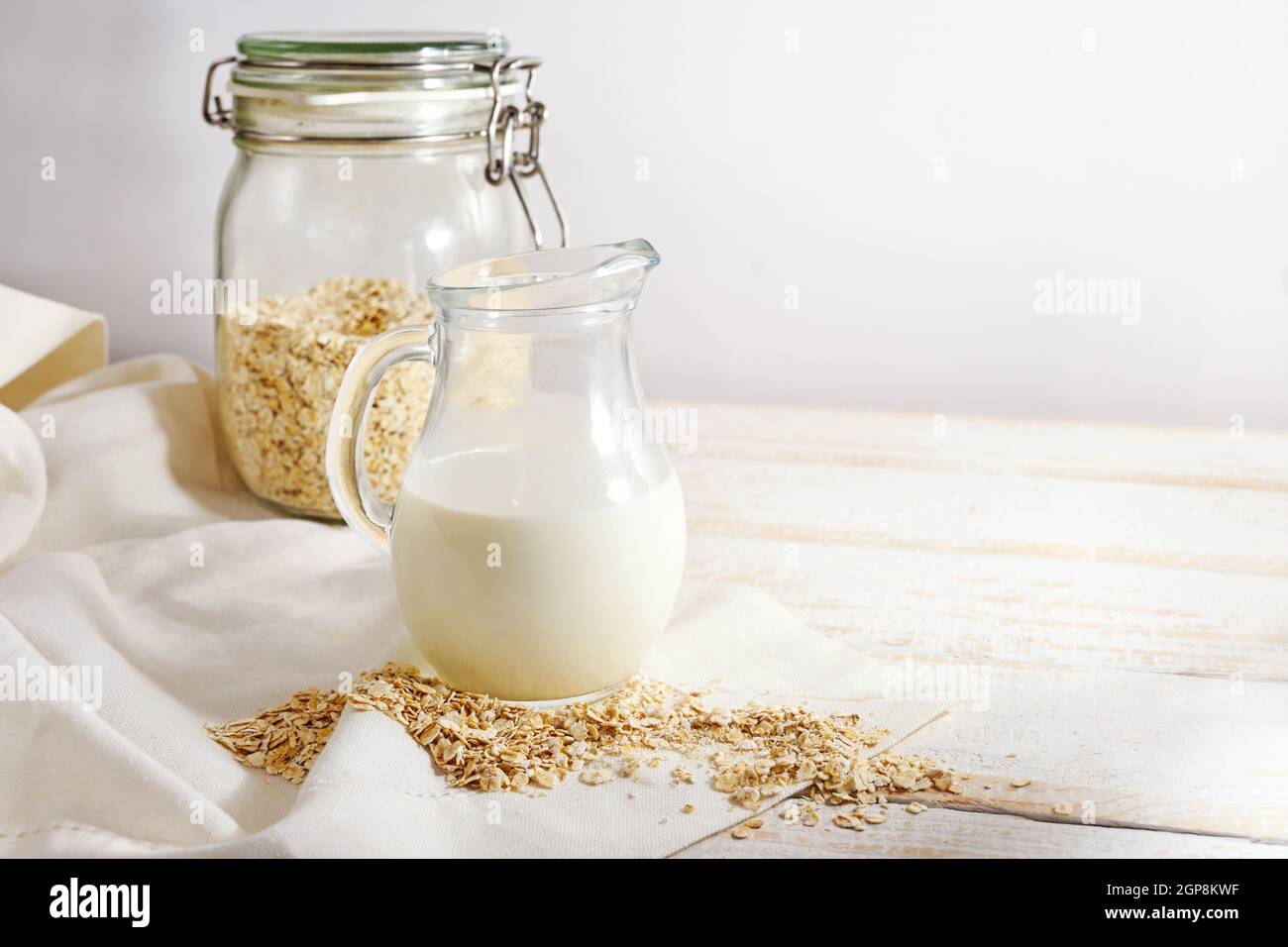 Vegane Hafermilch, eine gesunde Alternative ohne tierische Milchprodukte in einem Glaskrug auf einem hellen Holztisch, Kopierraum, ausgewählter Fokus, enge Tiefe o Stockfoto