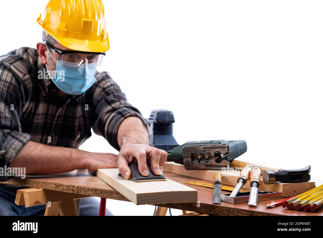 Zimmermann bei der Arbeit isoliert auf weißem Hintergrund, trägt Helm, Brille, Lederhandschuhe und OP-Maske, um Coronavirus-Infektion zu verhindern. Preve Stockfoto