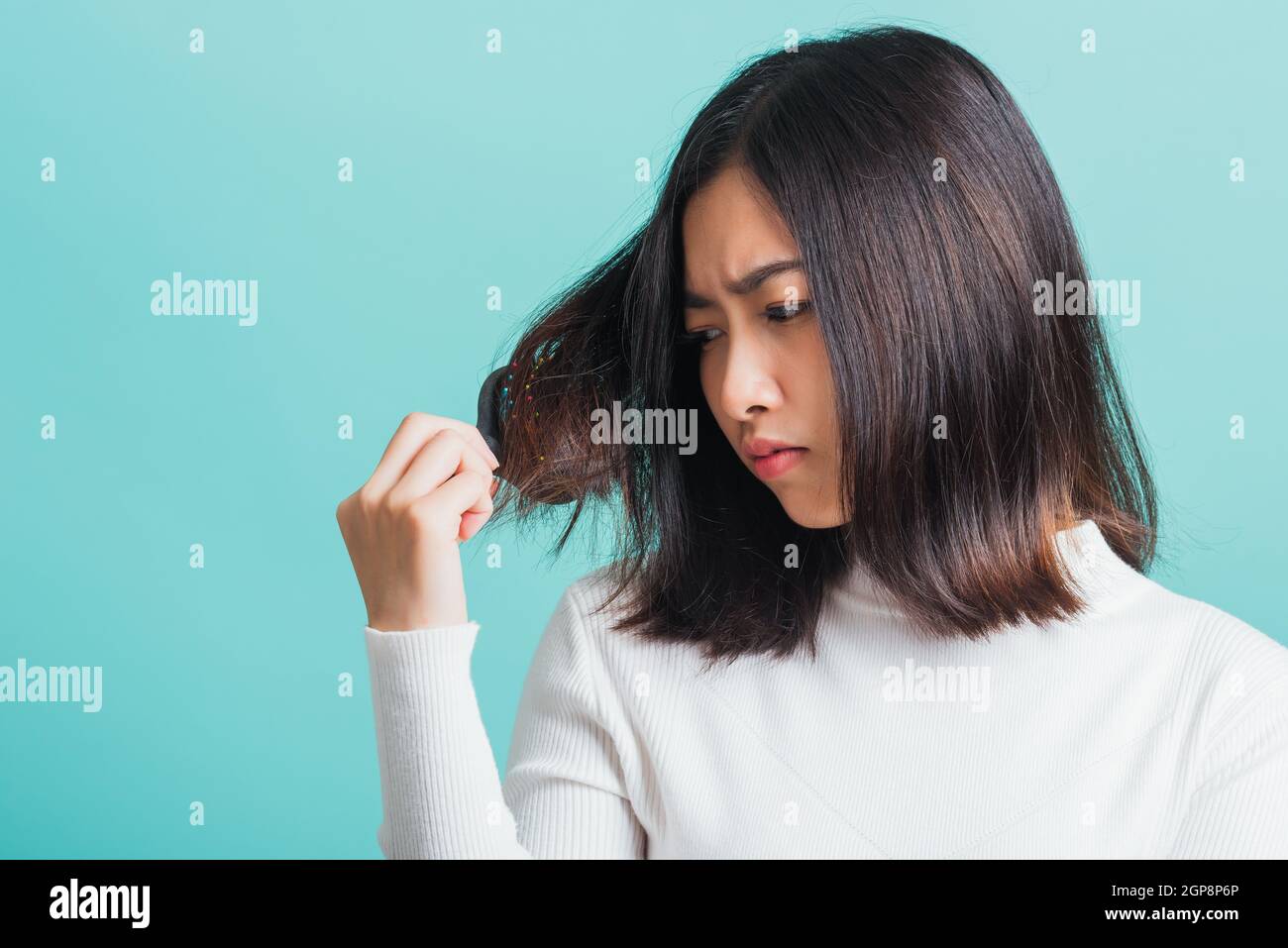 Junge schöne asiatische Frau aufgeregt mit einem Kamm und Problem Haar, Porträt weiblich schockiert leiden an Haarausfall Problem, Studio erschossen auf einem BL isoliert Stockfoto