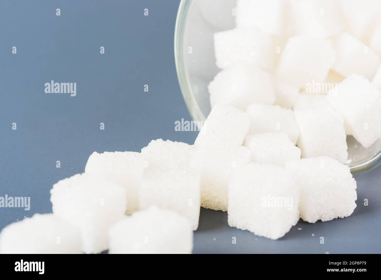 Weißer Zuckerwürfel süße Lebensmittel Zutat aus dem Glas verschüttet, Studio Schuss isoliert auf einem grauen Hintergrund, Minimal Gesundheit hohes Blutrisiko von Diabetes Stockfoto