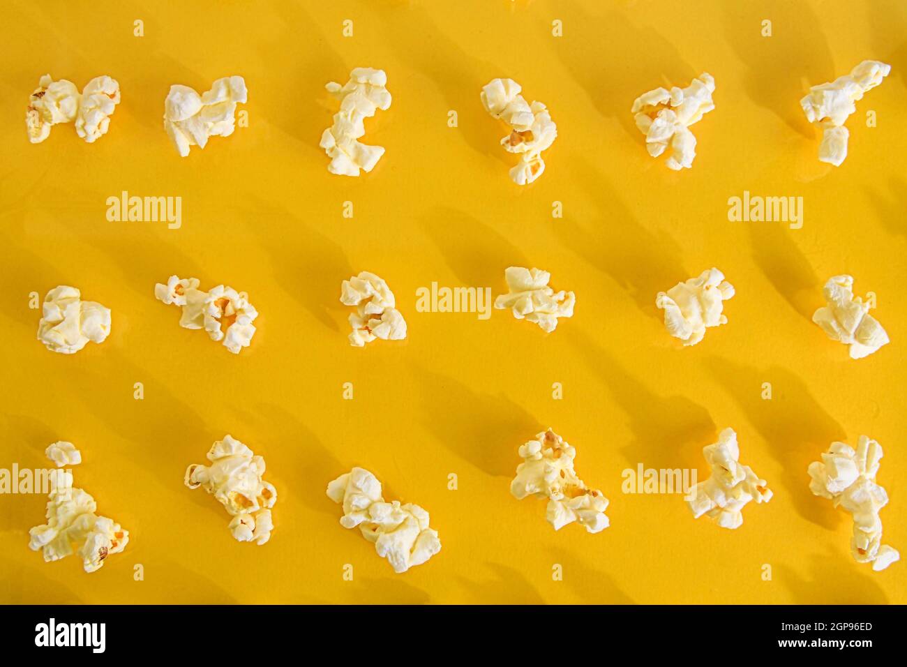 Nahaufnahme von Popcorn auf pastellgelbem Hintergrund. Kinokonzept mit vielen flauschigen Popcorn auf gelbem Retro-Hintergrund. Stockfoto