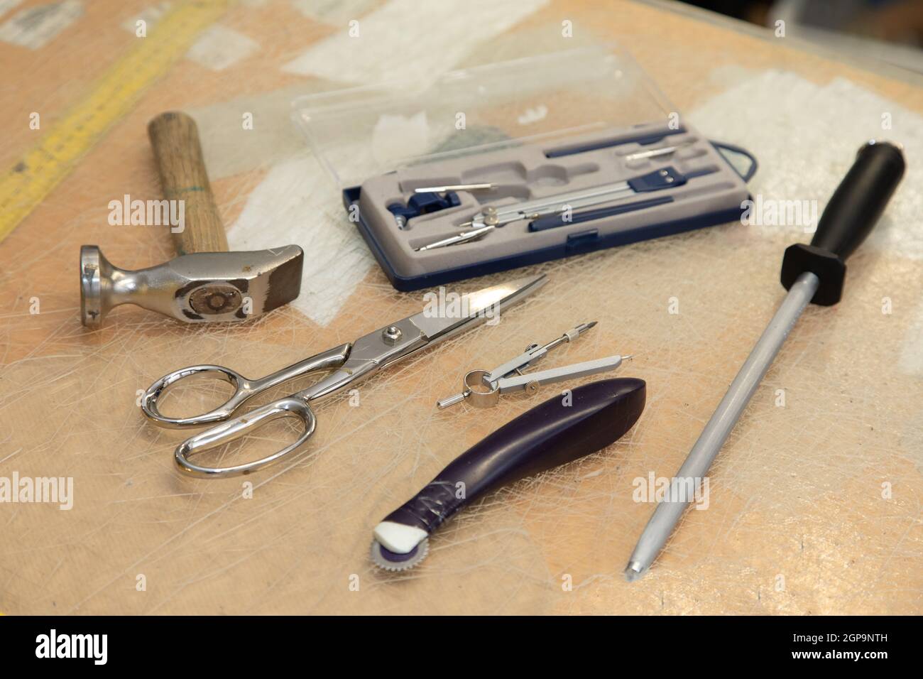 Schuhmacher hämmern Werkzeug, Kreis, Schere und ein Maßband auf einem Schreibtisch. Symbolisch für Handwerker und ihren Arbeitsplatz. Stockfoto