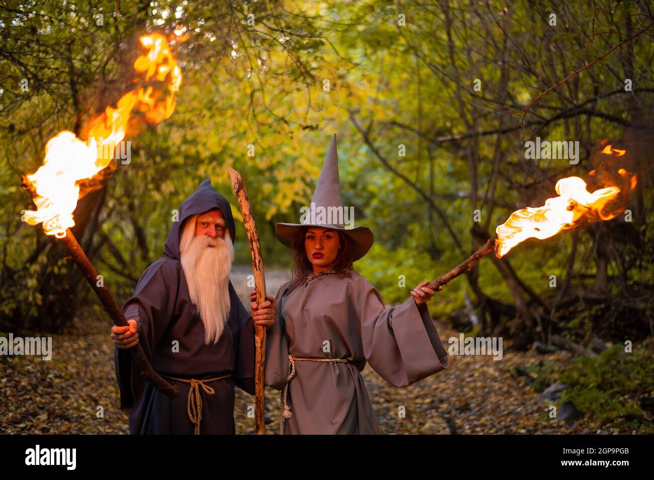 Zauberin und Zauberin im Herbstwald. Ältere Männer und Frauen in Karnevalskostümen für halloween Stockfoto