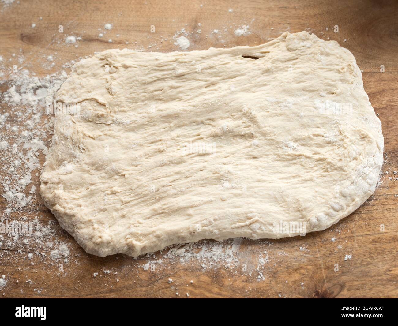 Teigverarbeitung mit Mehl für ein hausgemachtes Baguette auf einer hölzernen Küchentheke. Stockfoto
