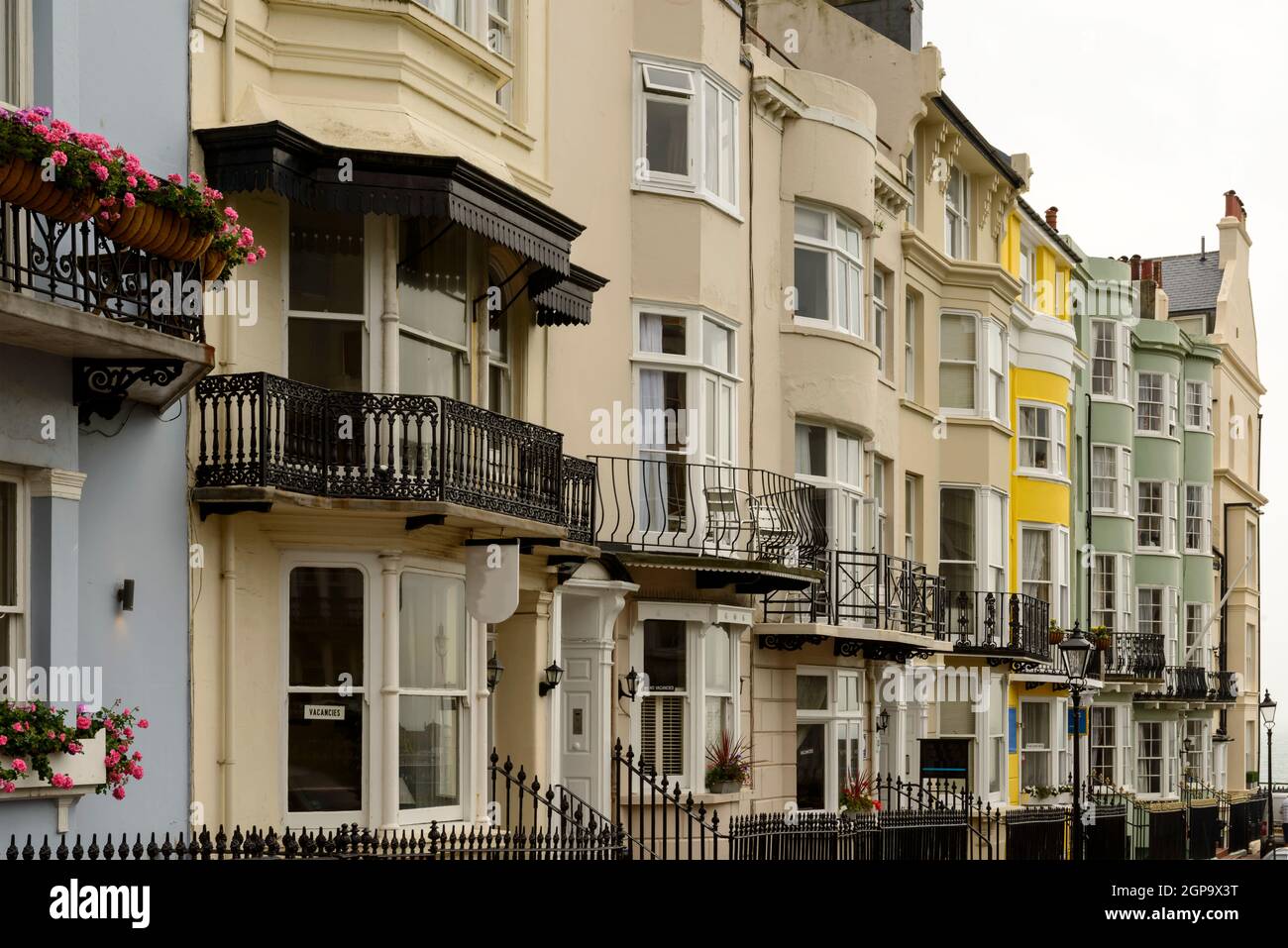Verkürzung von Bogenfenstern an Fassaden alter Häuser auf einer bergauf führenden Straße in touristischer Seestadt Brighton, East Sussex Stockfoto